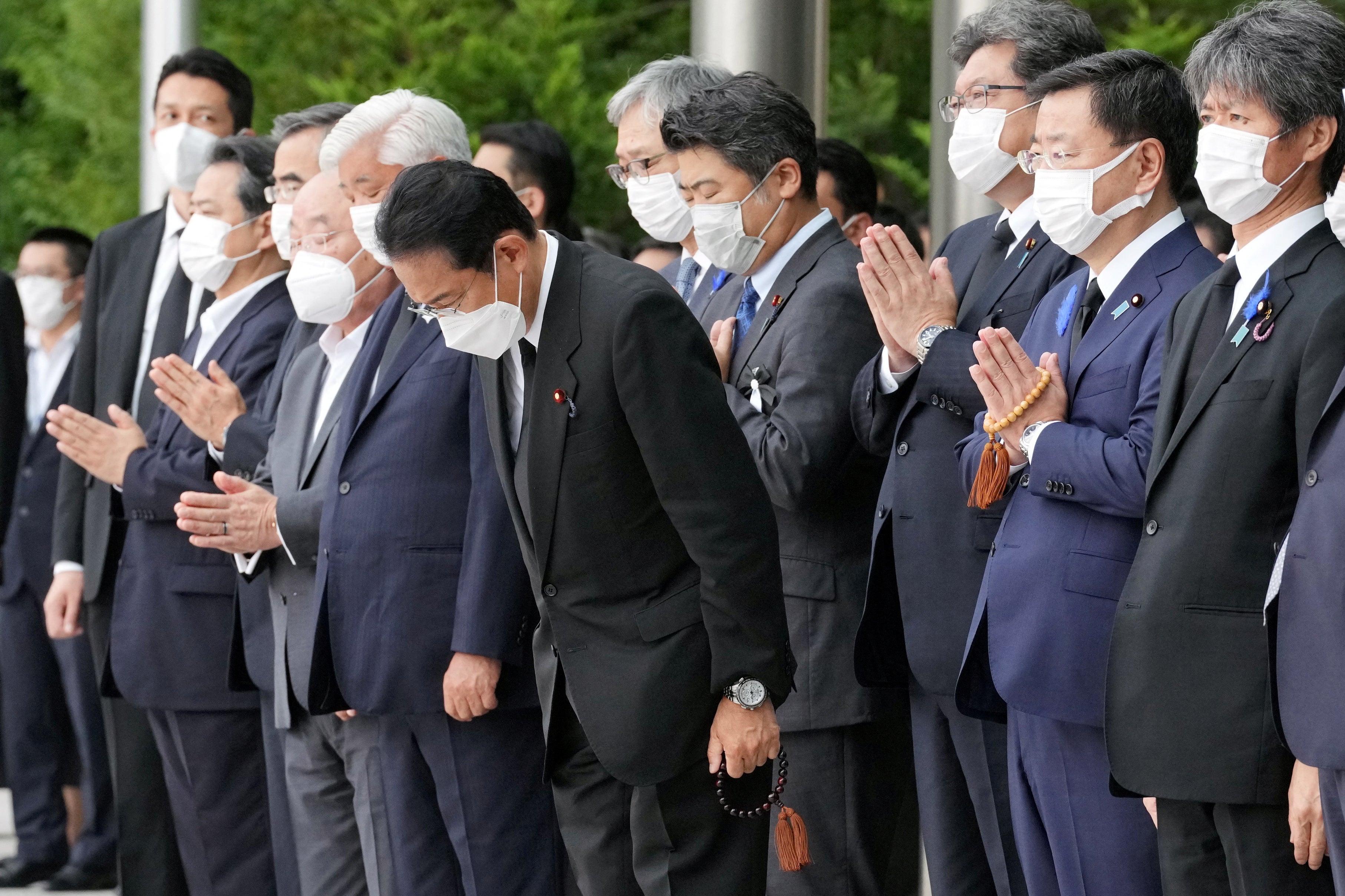 Japan’s prime minister Fumio Kishida, alongside officials and employees, offers prayers as the funeral procession passes
