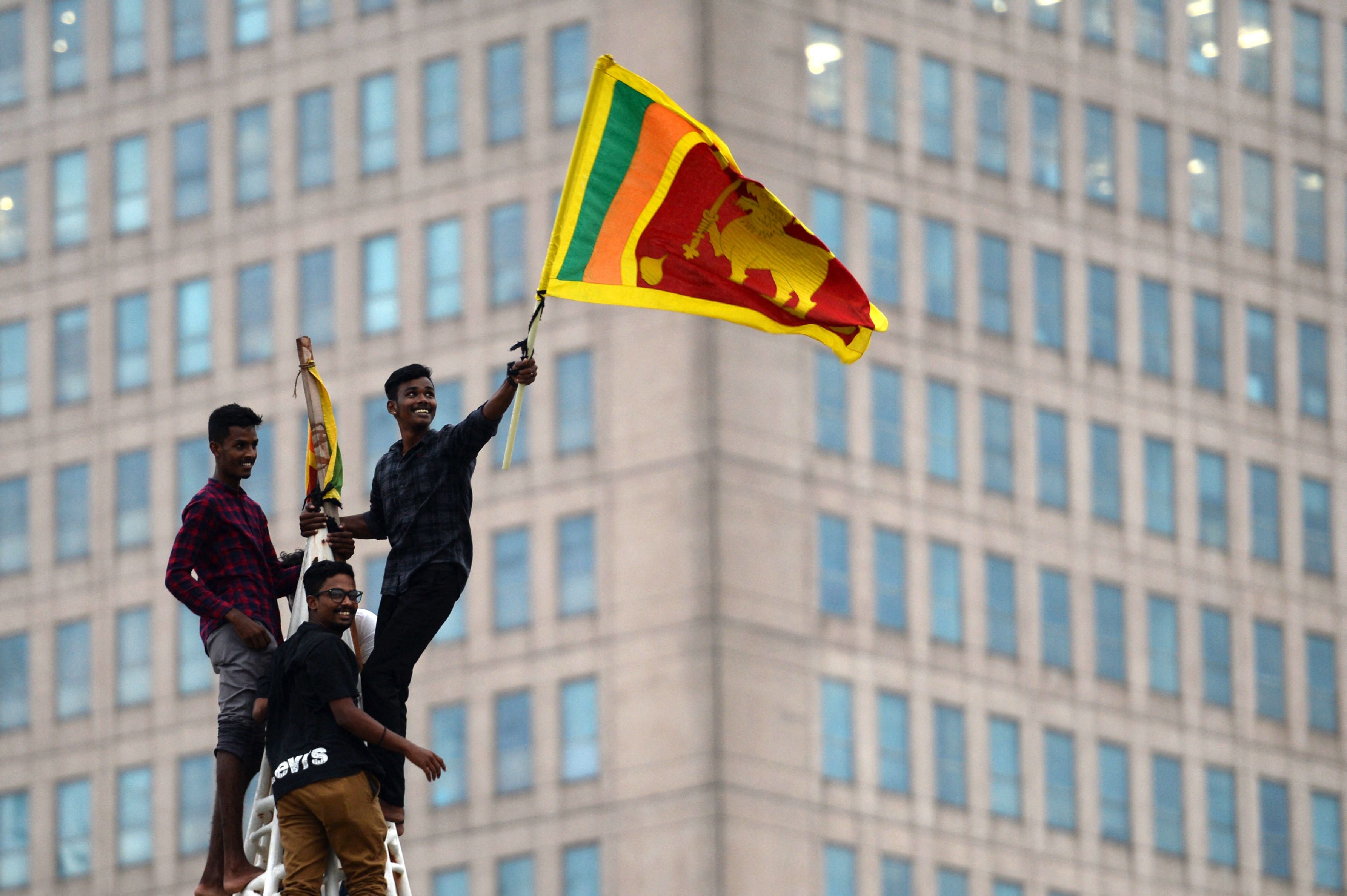 A man waves Sri Lanka’s national flag after climbing a tower near the presidential secretariat in Colombo on 11 July after it was overrun by anti-government protesters