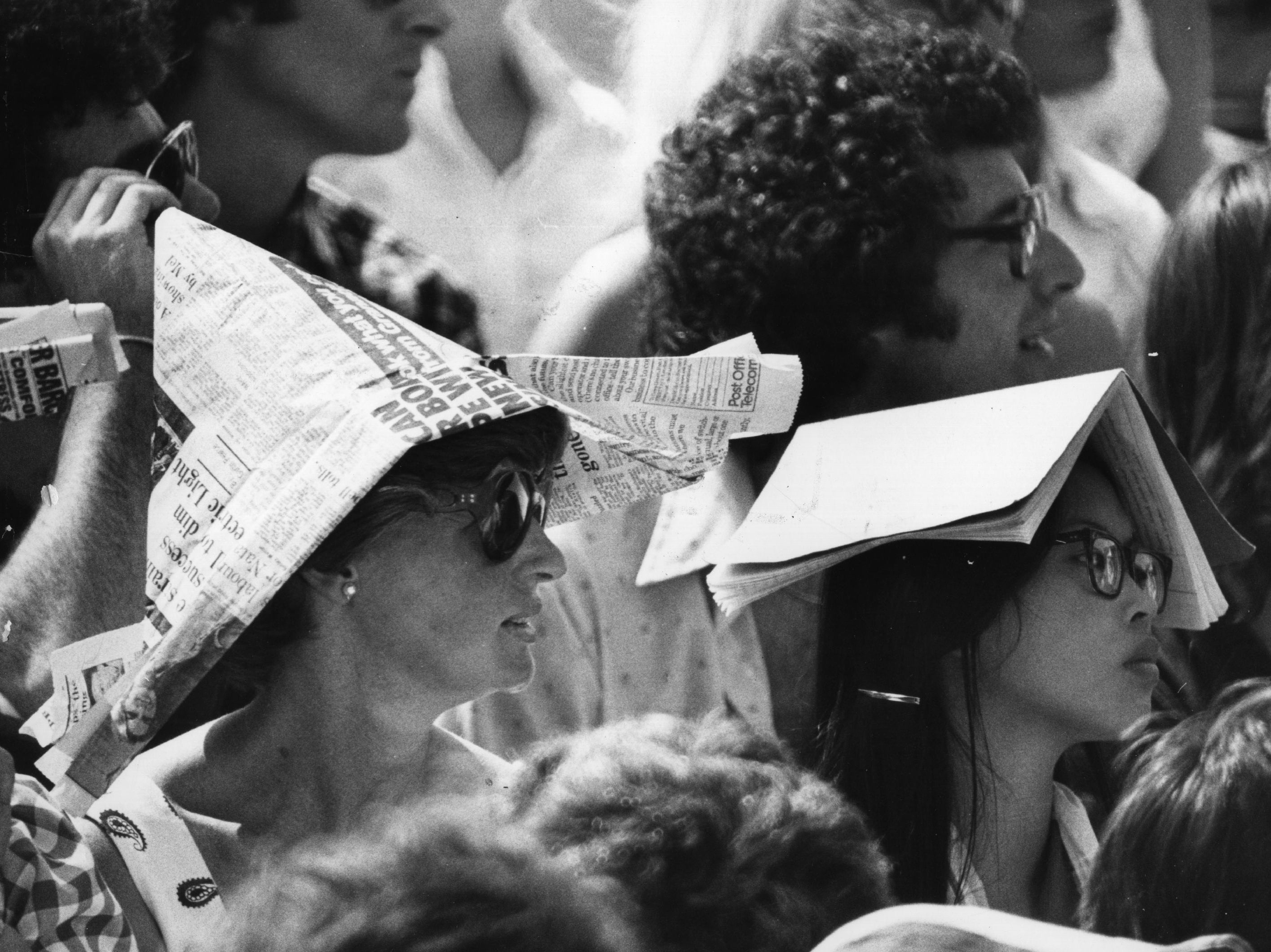Spectators at Wimbledon protect themselves from the sun wearing newspaper hats and books on their heads during the heatwave