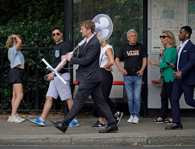 An office worker carries a fan through central London (Yui Mok/PA)