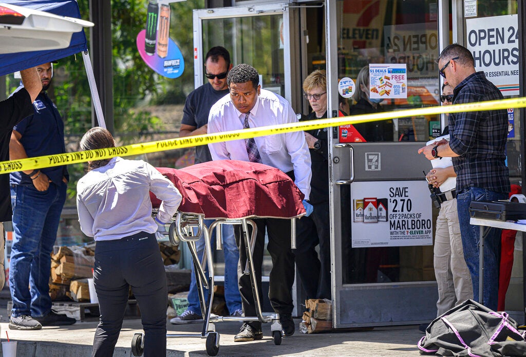 Authorities remove a body from a 7-Eleven after a clerk was fatally shot on Monday, July 11, 2022, during a robbery in Brea, Calif.