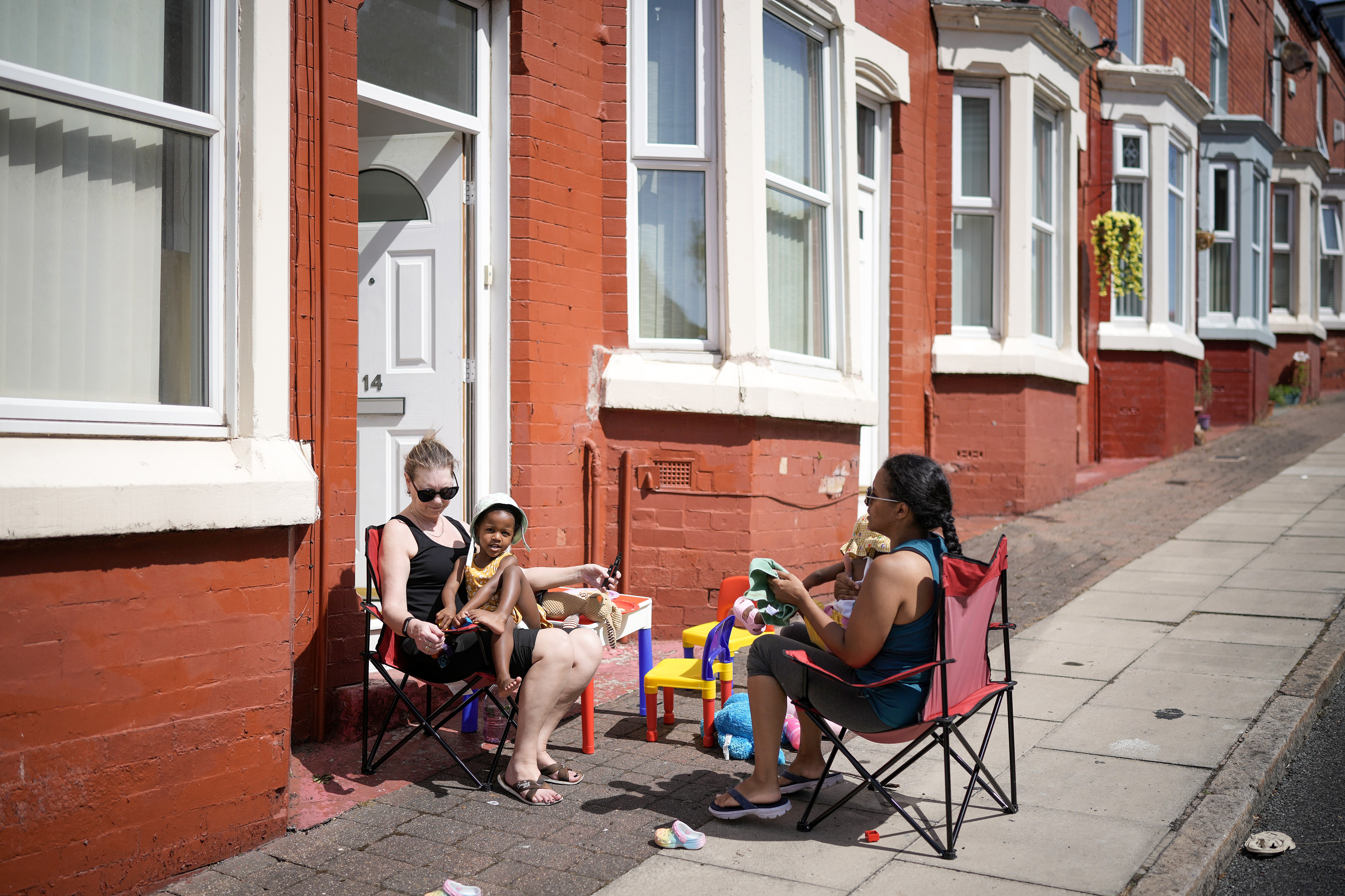 People enjoy the hot weather outside their homes in Liverpool on Monday