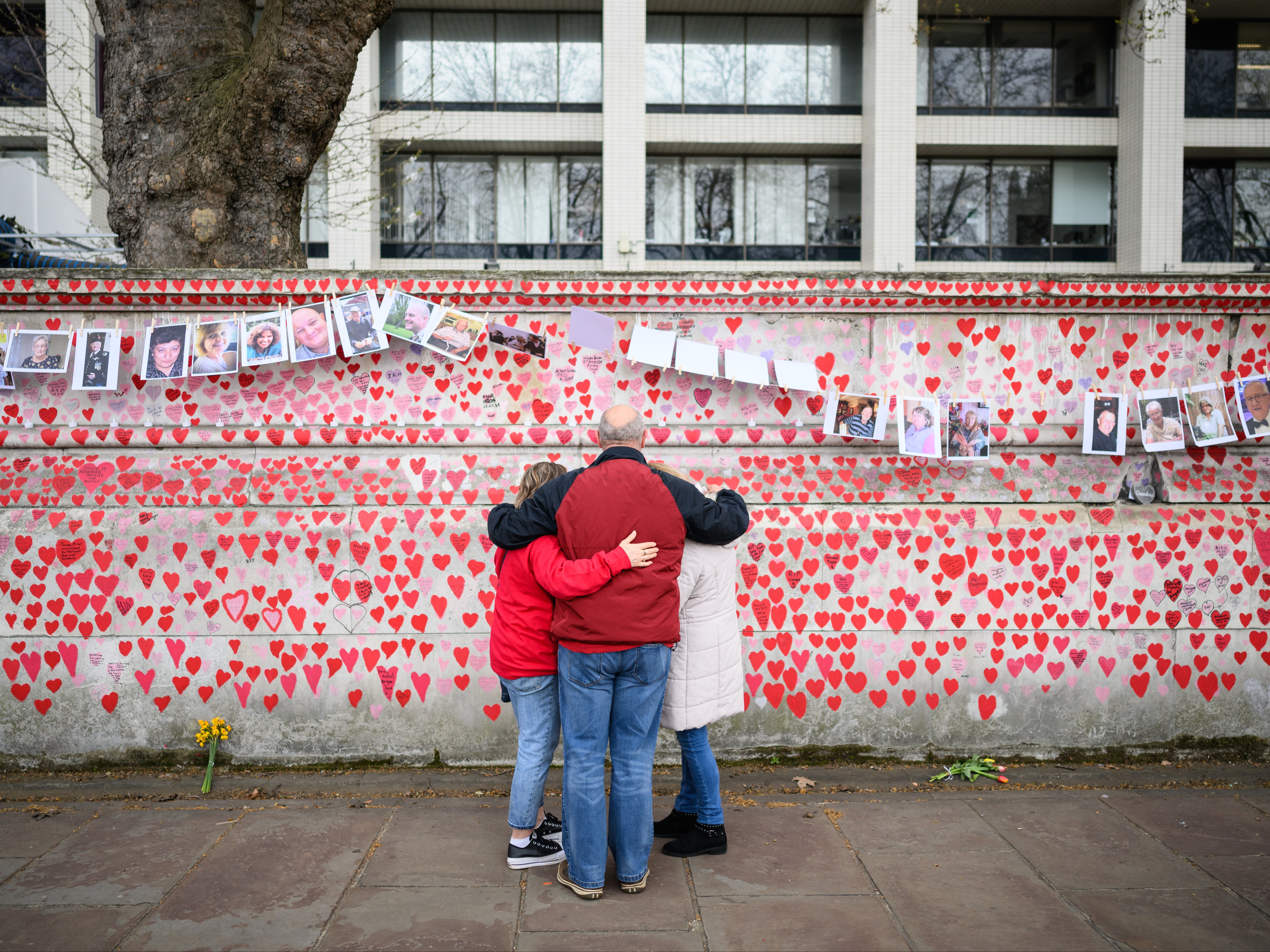 <p>Members of the public view the photos of some of those who died during the Covid-19 pandemic</p>