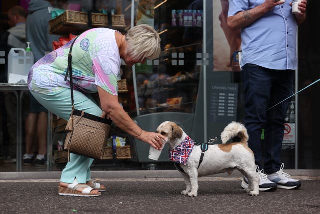 A woman gives her dog a drink of water during the hot weather (Liam McBurney/PA)
