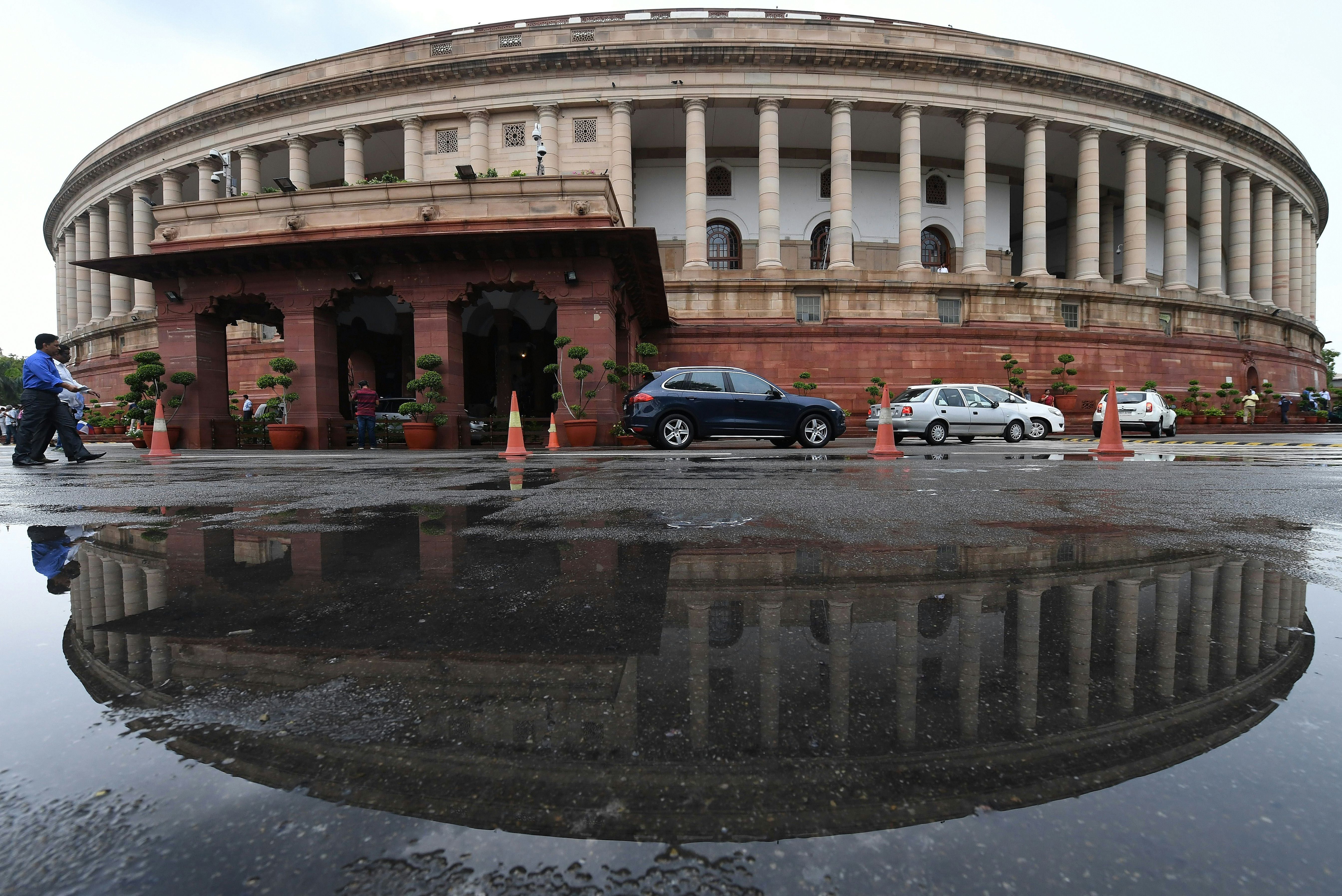 The Indian Parliament building is reflected in a puddle after heavy rain during the monsoon session of the Indian Parliament in New Delhi