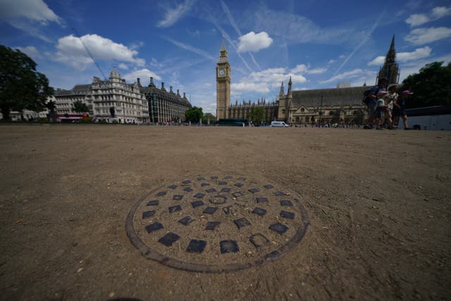 Parched earth in the normally green surroundings of Parliament Square in London (Yui Mok/PA)