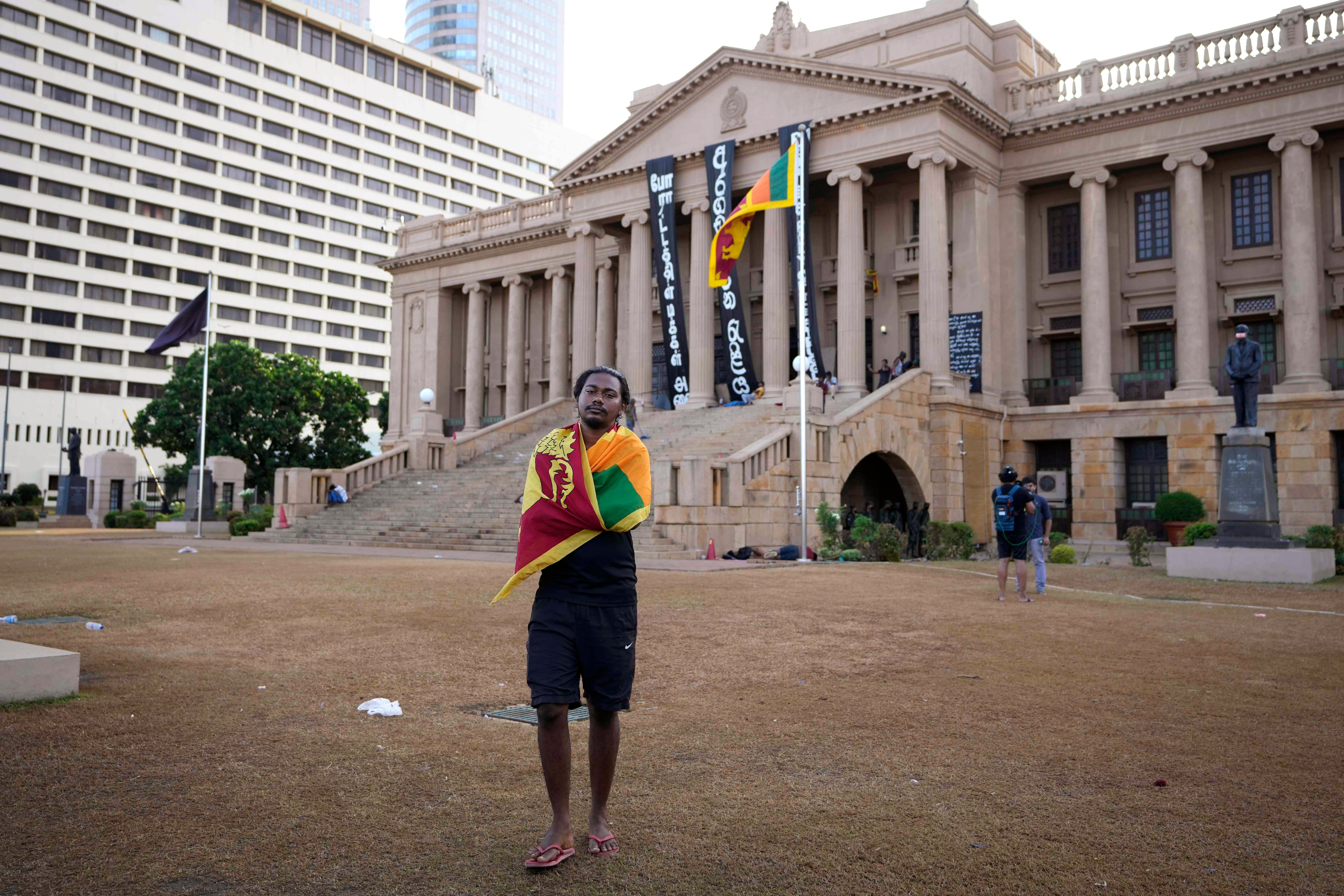 A protester wraps the national flag around his shoulders in the compound of the presidential secretariat in Colombo, Sri Lanka on 15 July