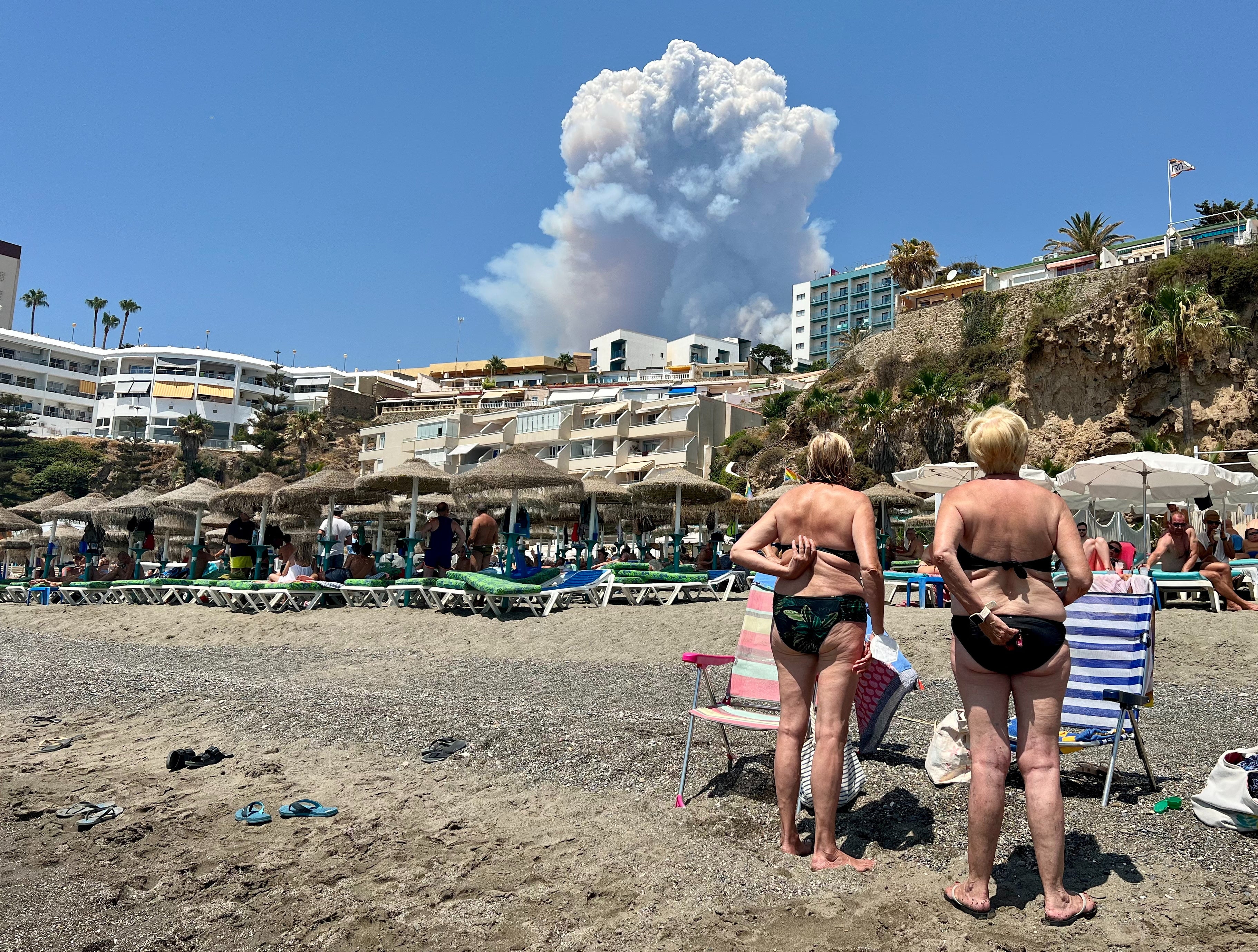 Bathers in Torremolinos watch plumes of smoke caused by a wildfire