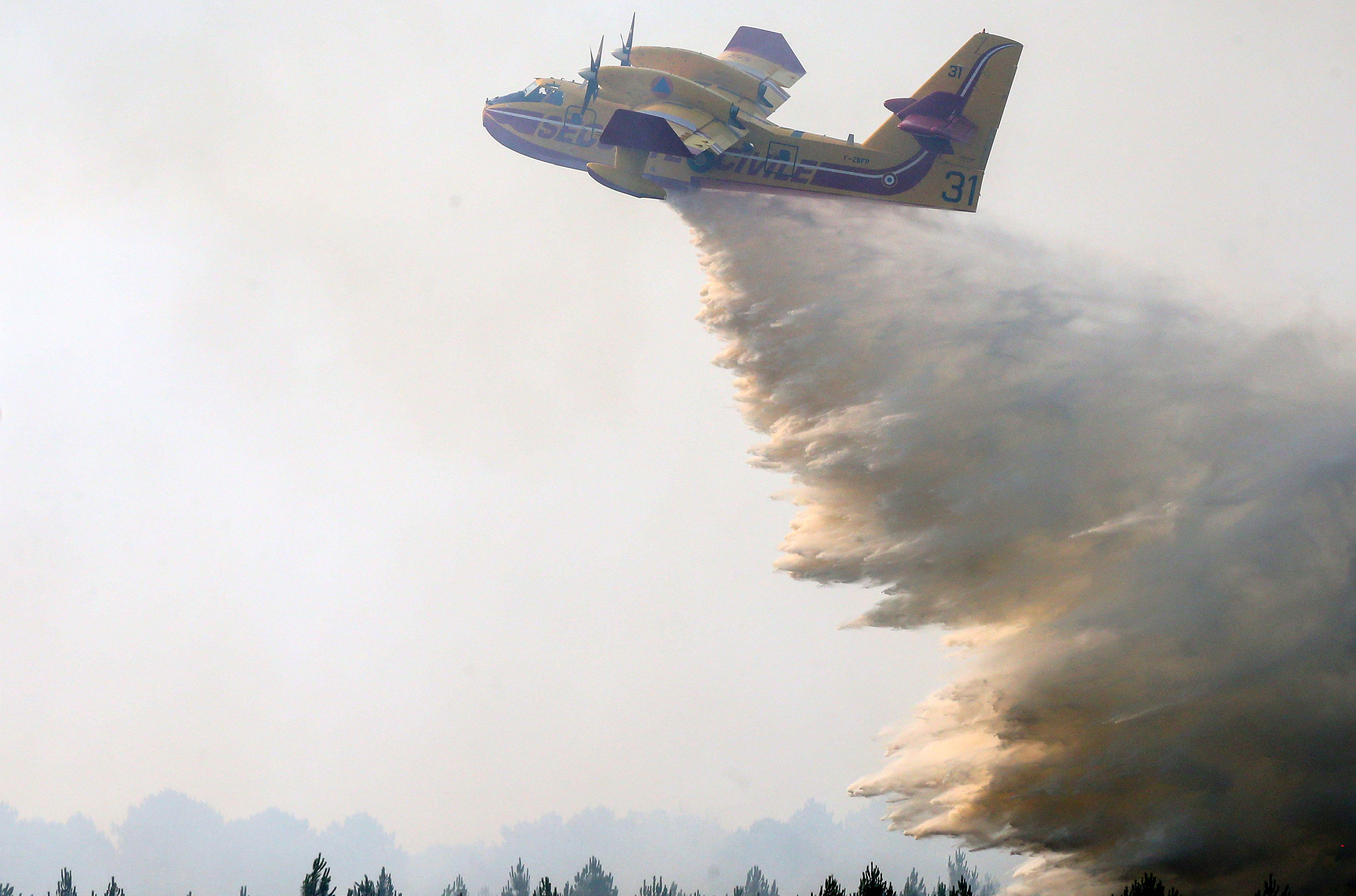 A firefighting aircraft dumps water over a wildfire in Landiras, southwestern France