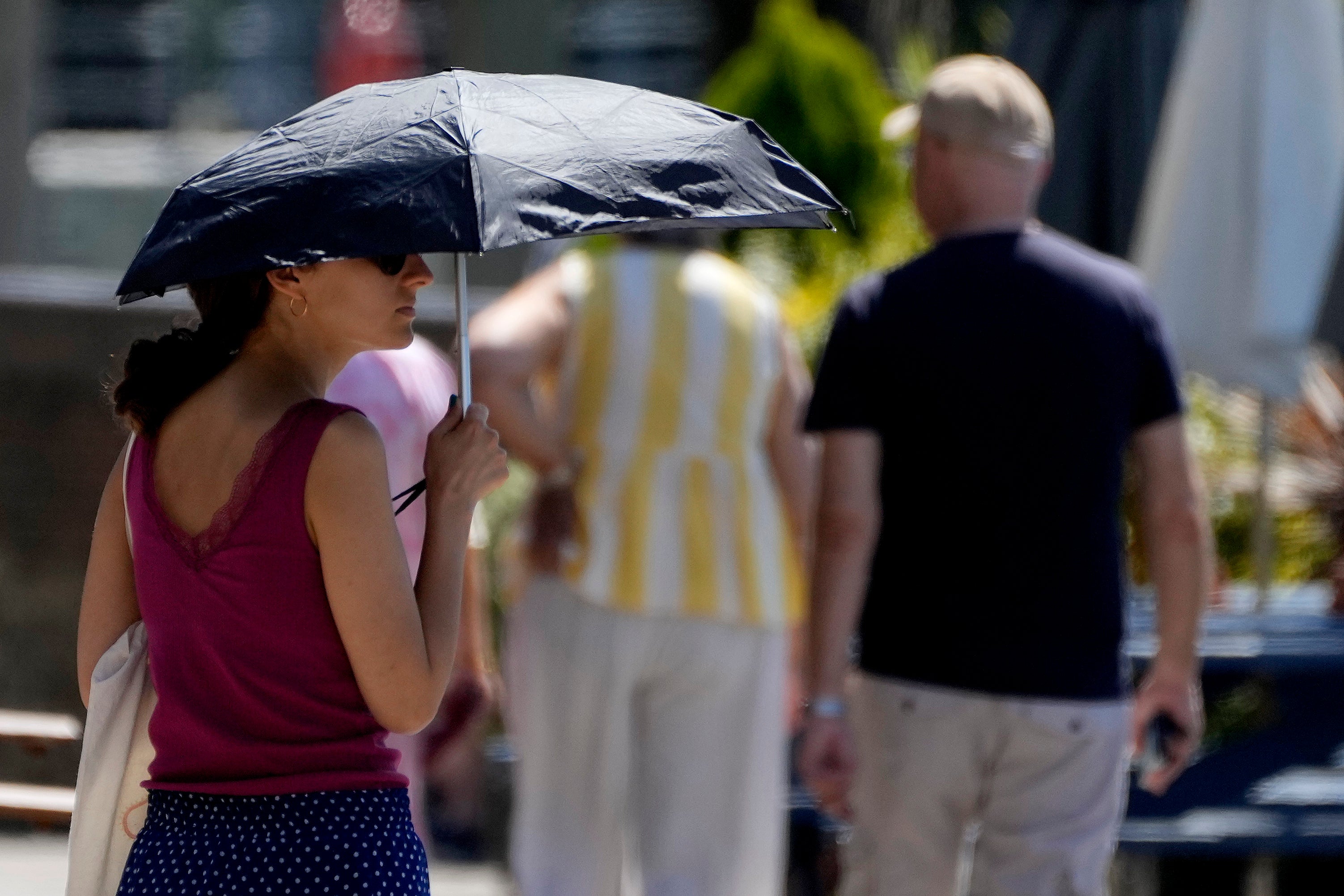 A woman shelters from the sun near Hammersmith in London on Friday