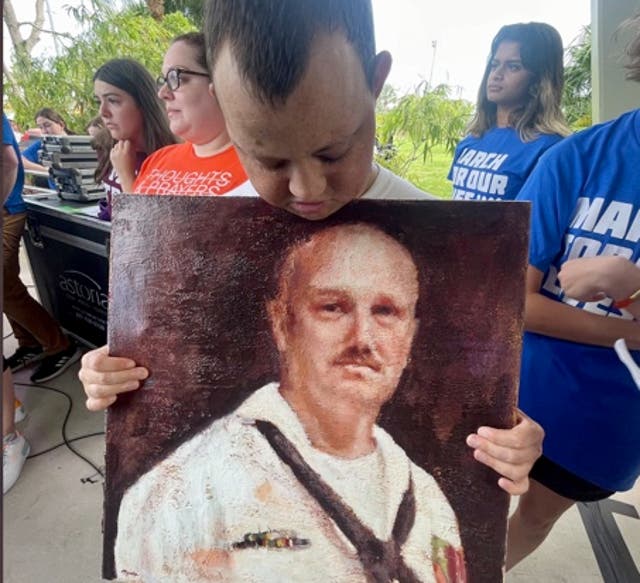 <p>Corey Hixon holds a drawing of his father Chris at the March for Our Lives rally in June 2022</p>
