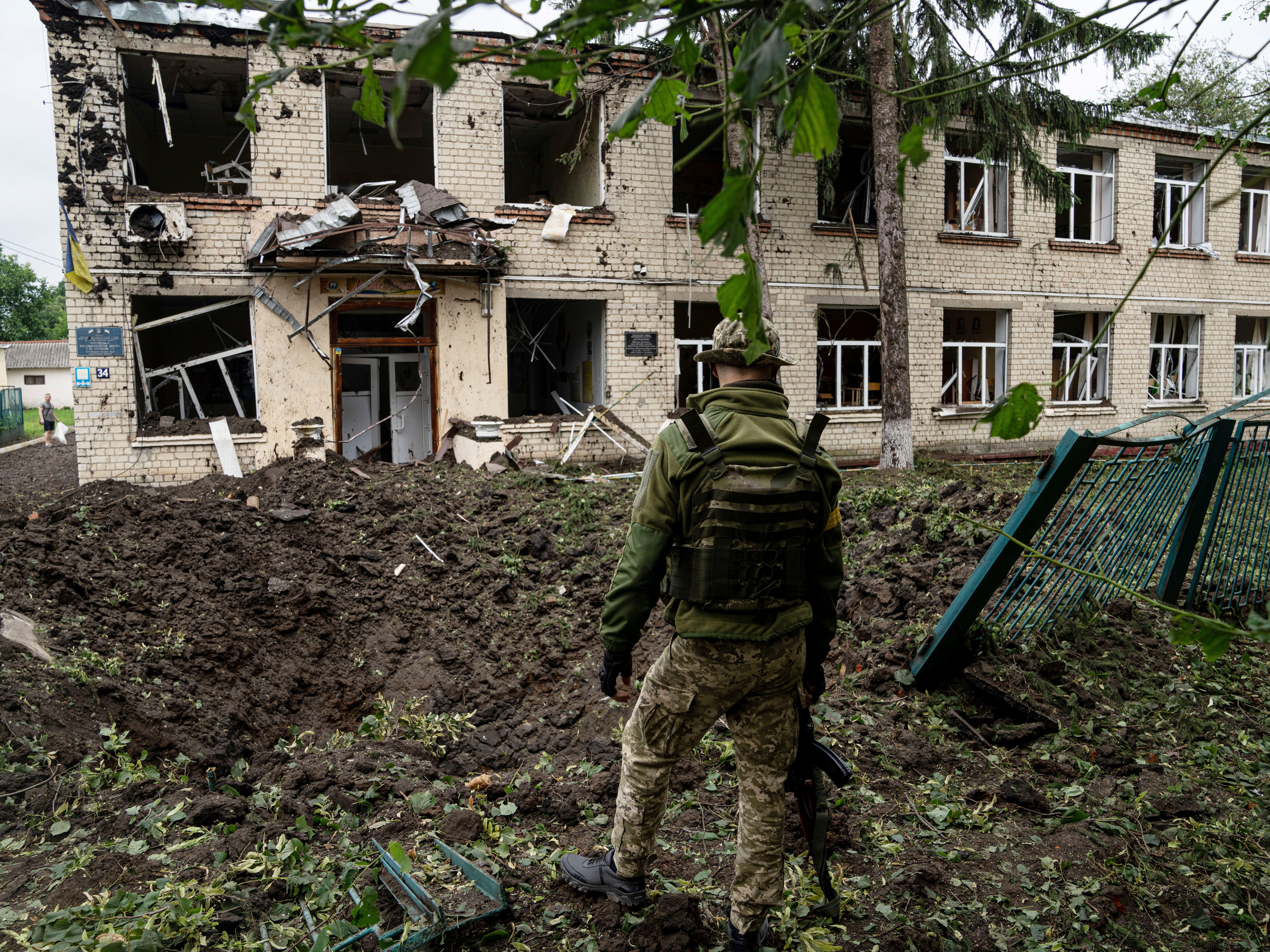 Russian shelling left a crater in the ground and damaged a school in Chuhuiv