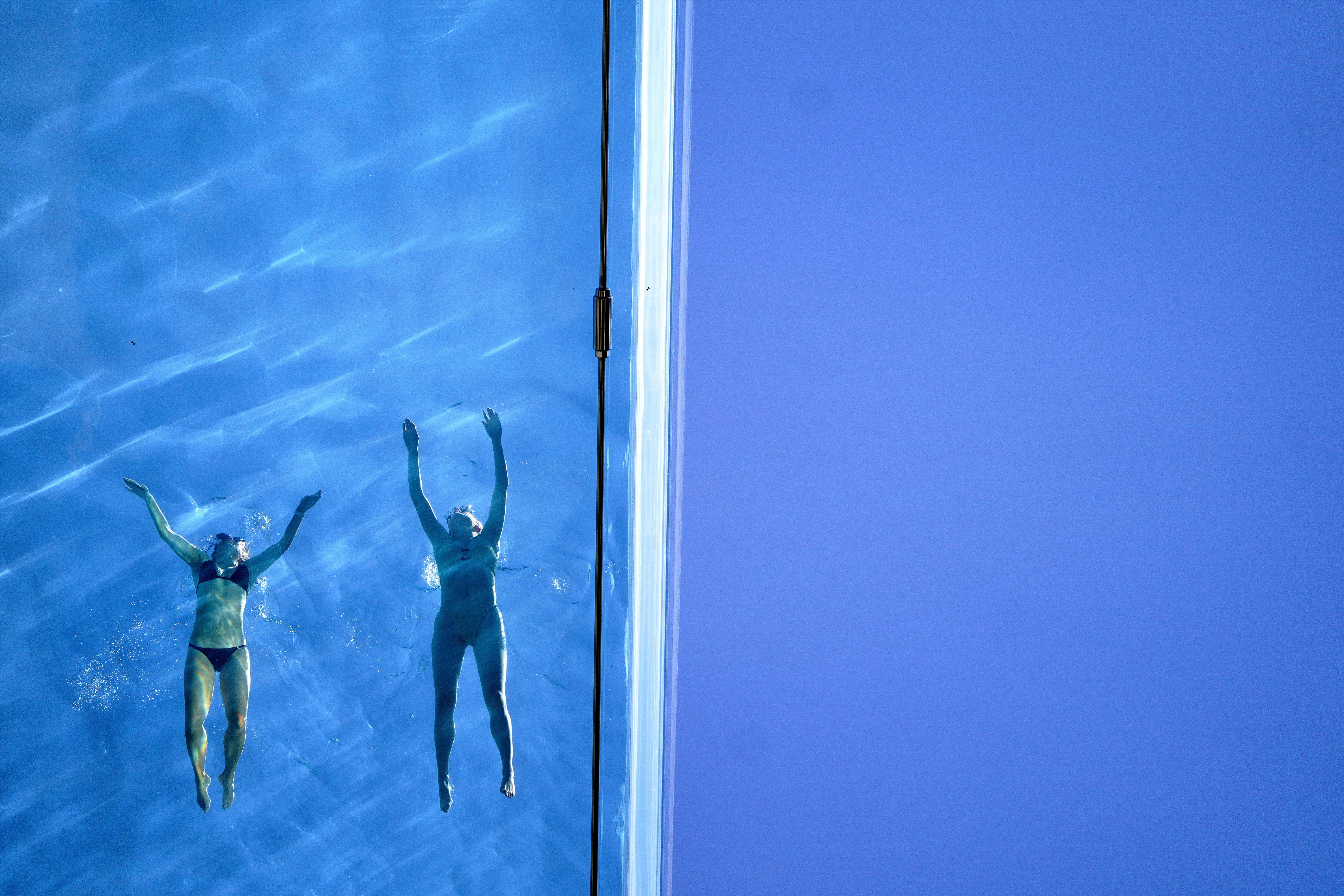Swimmers take a dip in the Sky Pool, a transparent swimming pool suspended 35 metres above ground between two apartment buildings in Nine Elms, central London (Victoria Jones/PA)