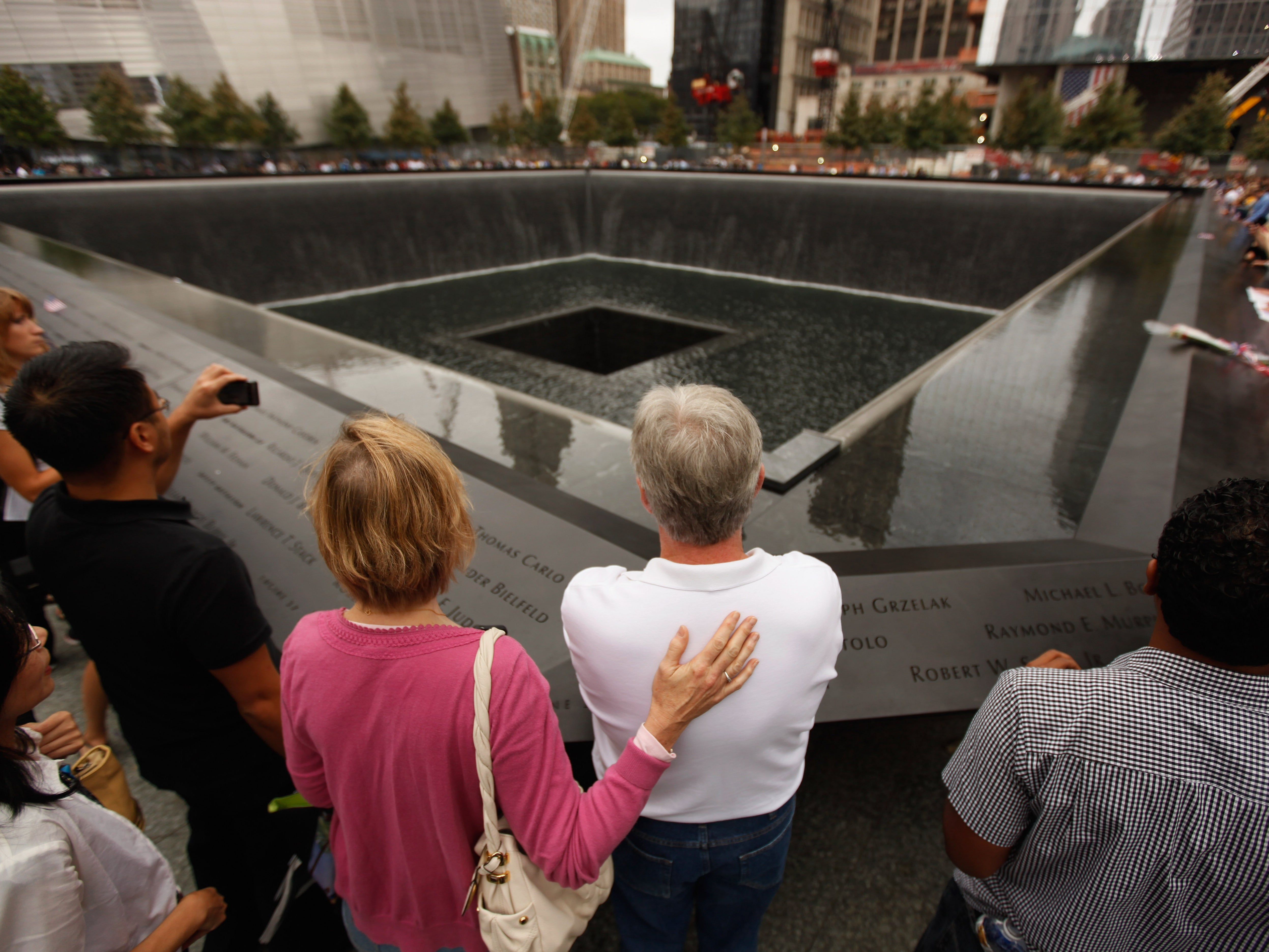 Family members of 9/11 victims stand at the edge of one of the memorial pools in New York City on the attack’s 10th anniversary in 2011