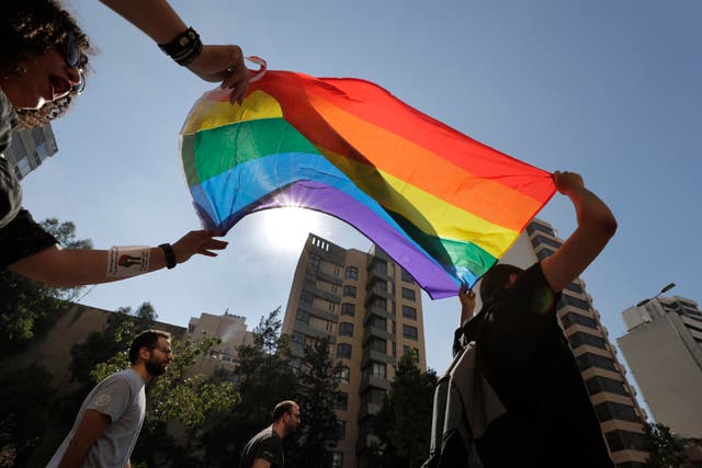<p>Activists hold up a Pride flag </p>