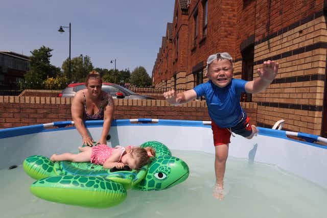 Emma Stewart with her children Caleb, 5, and Isla aged 2, cooling down in a swimming pool at their family home in Ardoyne, north Belfast. Picture date: Monday July 18, 2022.