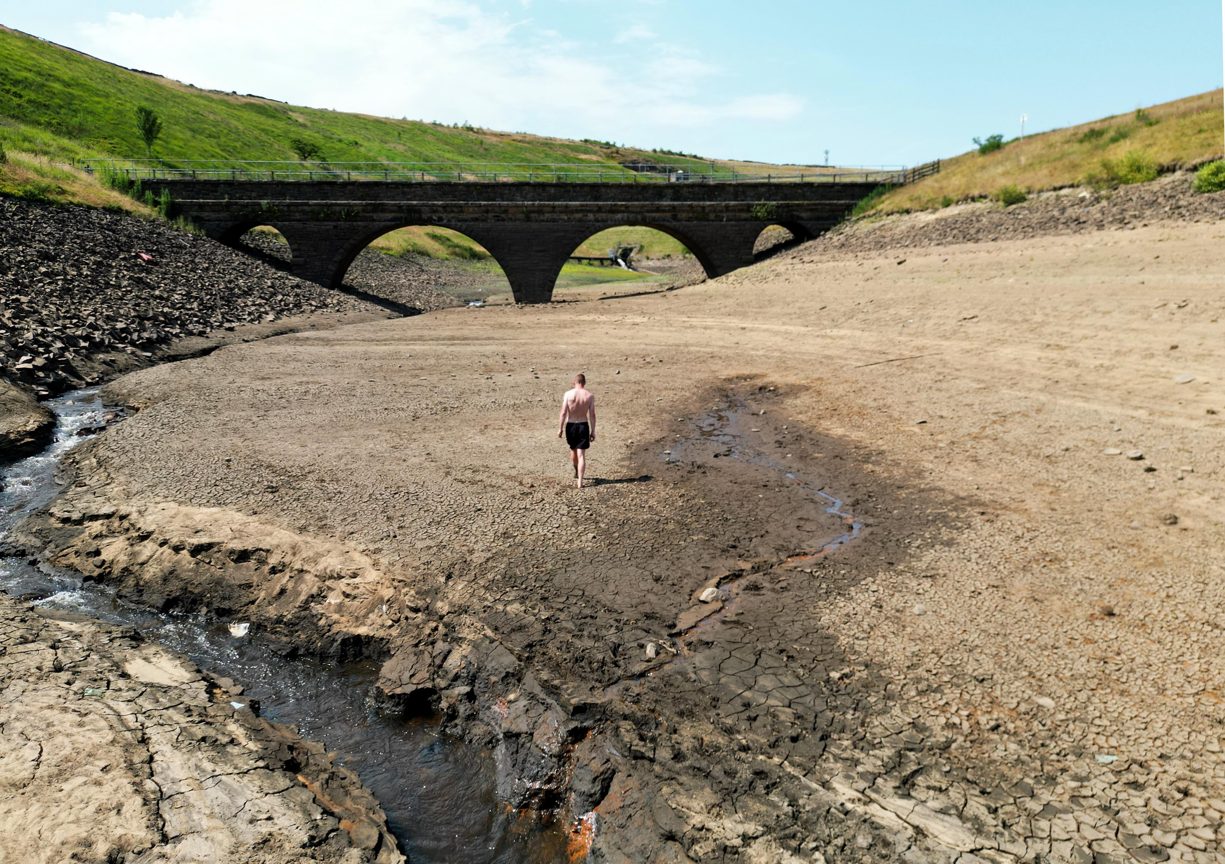 A person walks a dry bank of a tributary to the Dowry Reservoir close to Oldham (Danny Lawson/PA)