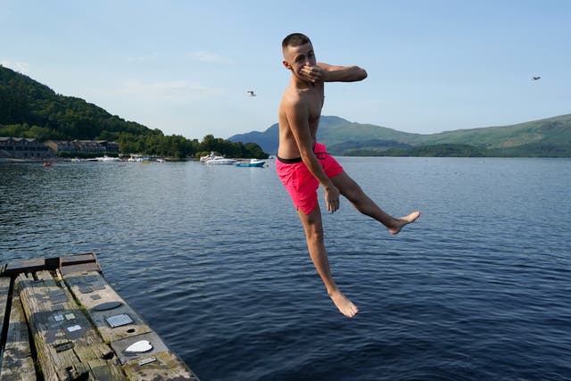 People jump from a pier into the water of Loch Lomond (Andrew Milligan/PA)