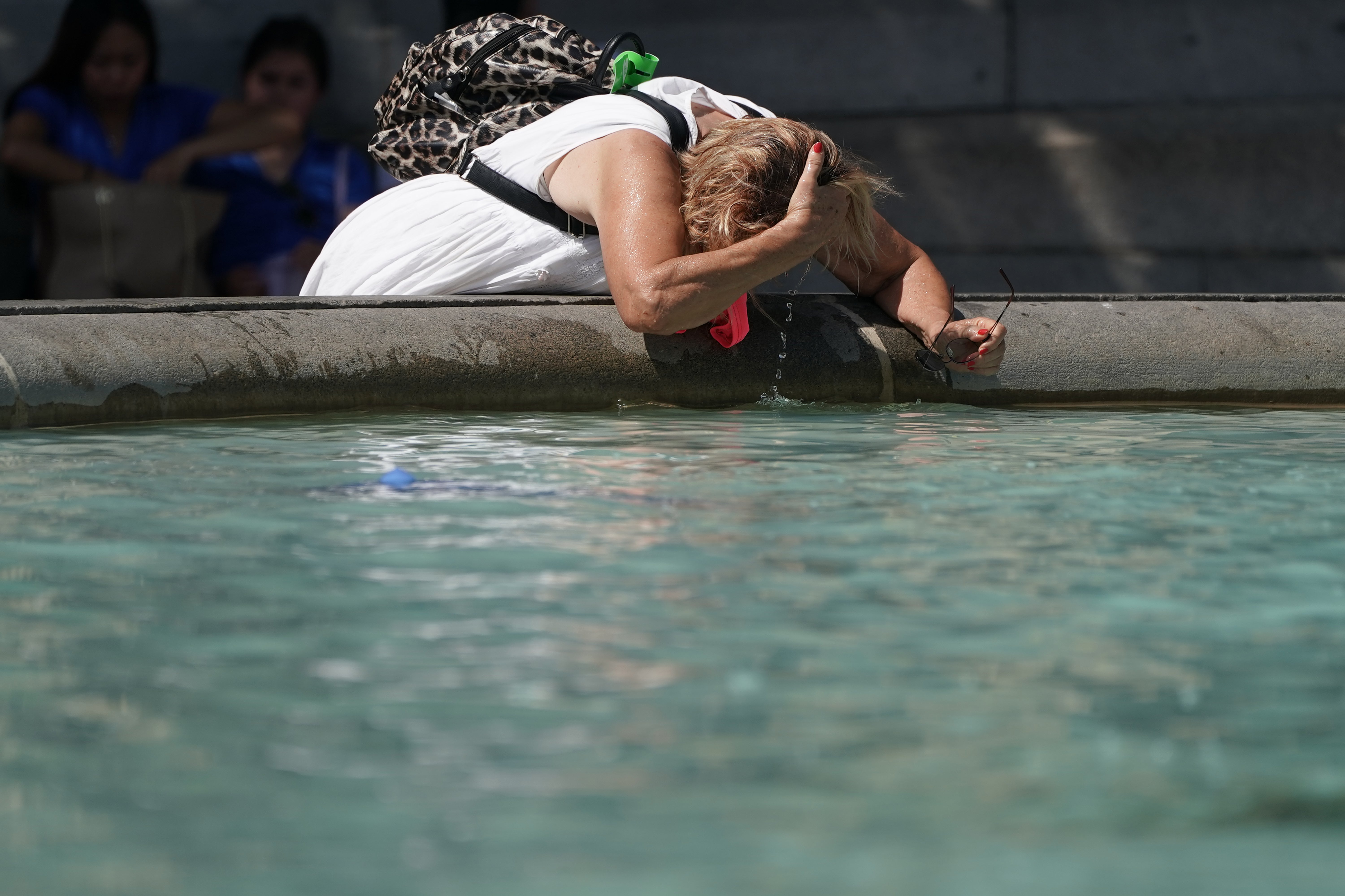 A person wets their hair in a fountain at Trafalgar Square in central London (Aaron Chown/PA)
