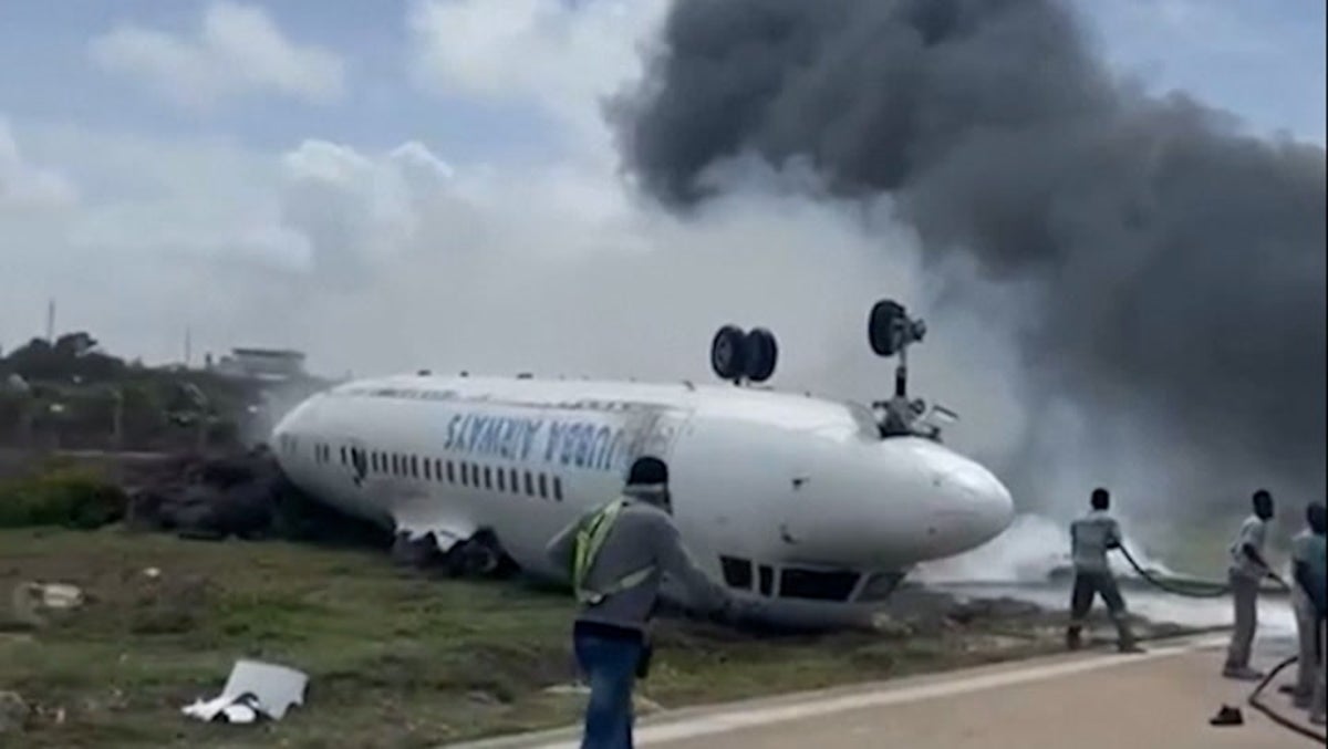 Firefighters tackle blaze by flipped-over plane in Somalia