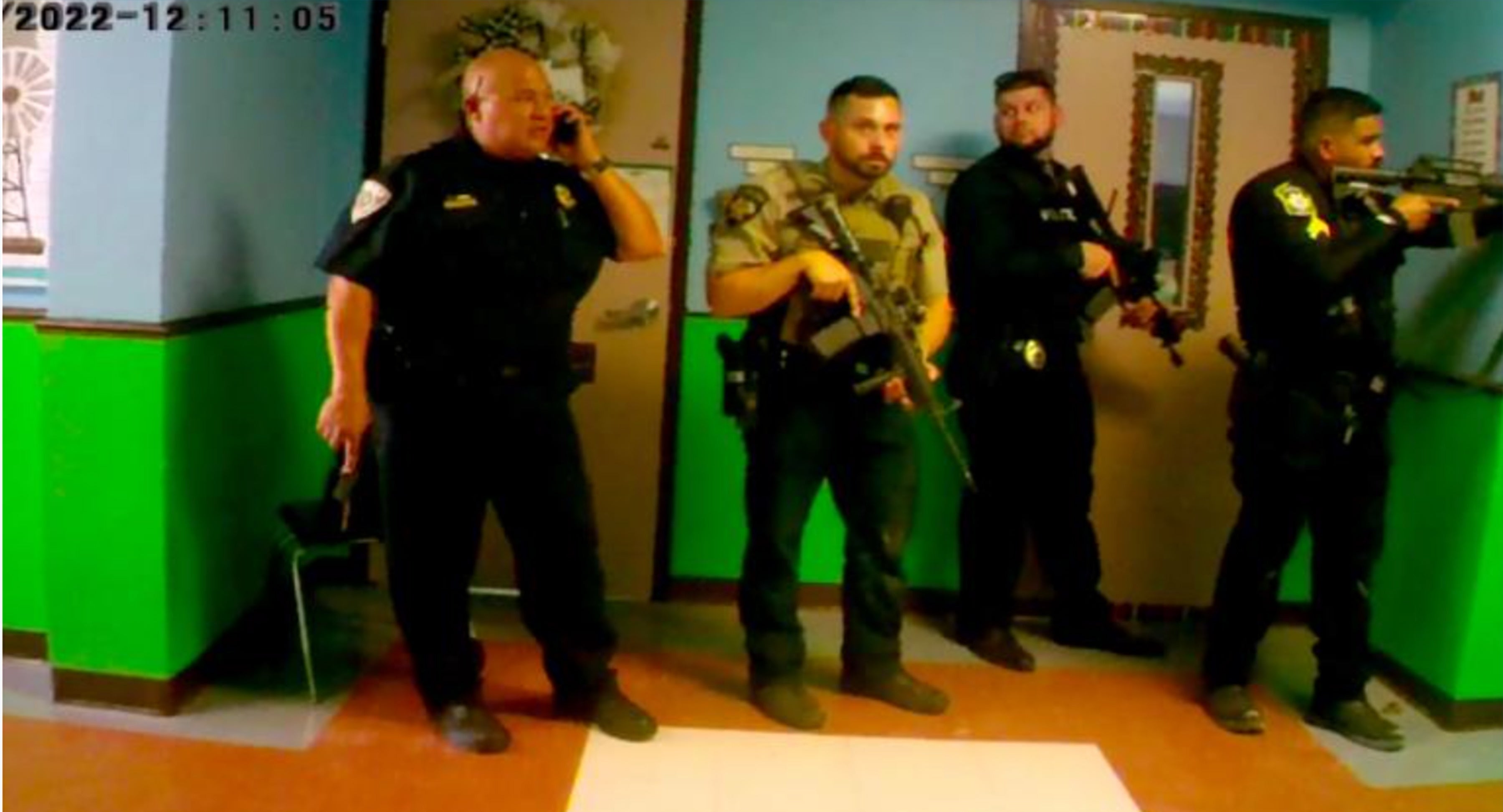 Law enforcement officers stand in the hallway of the school failing to enter as the shooting continues