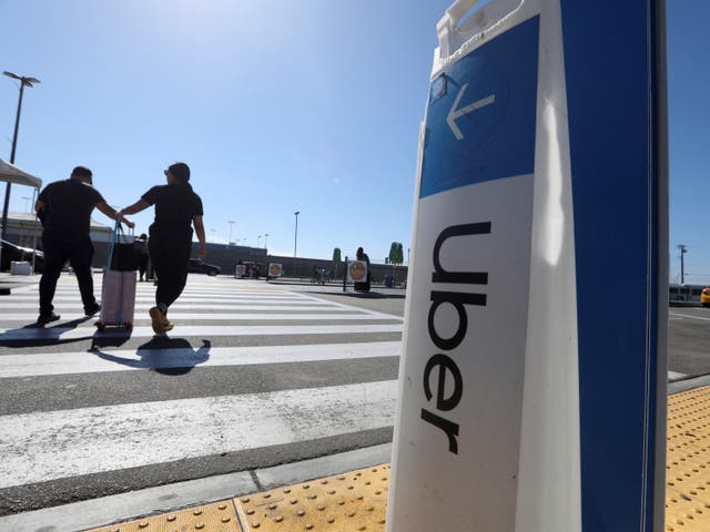 <p>Passengers walk near Uber signage after arriving at Los Angeles International Airport (LAX) in Los Angeles, California, U.S. July 10, 2022</p>