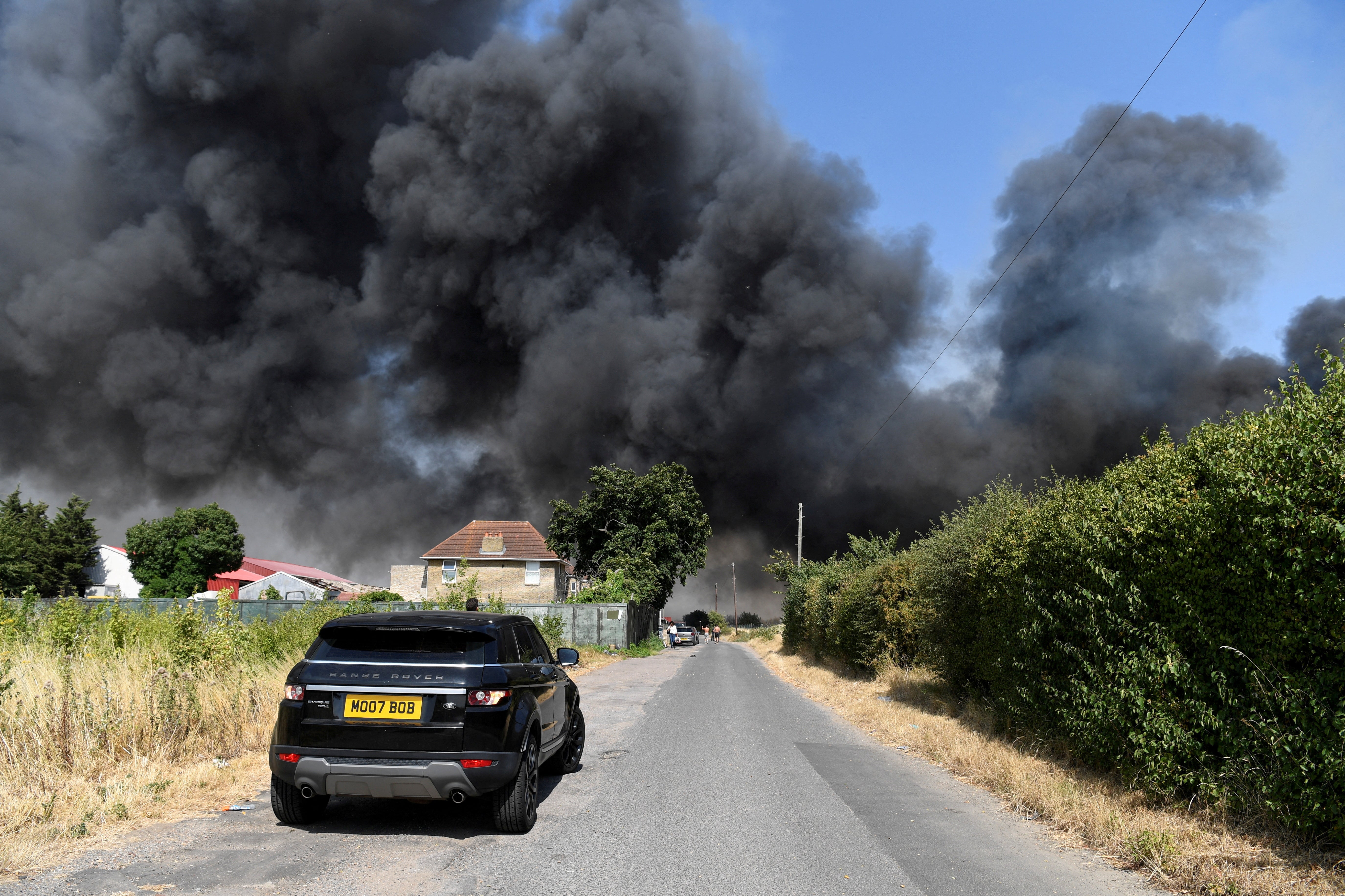 A car drives near a fire that burns during the heatwave, in Rainham, east London