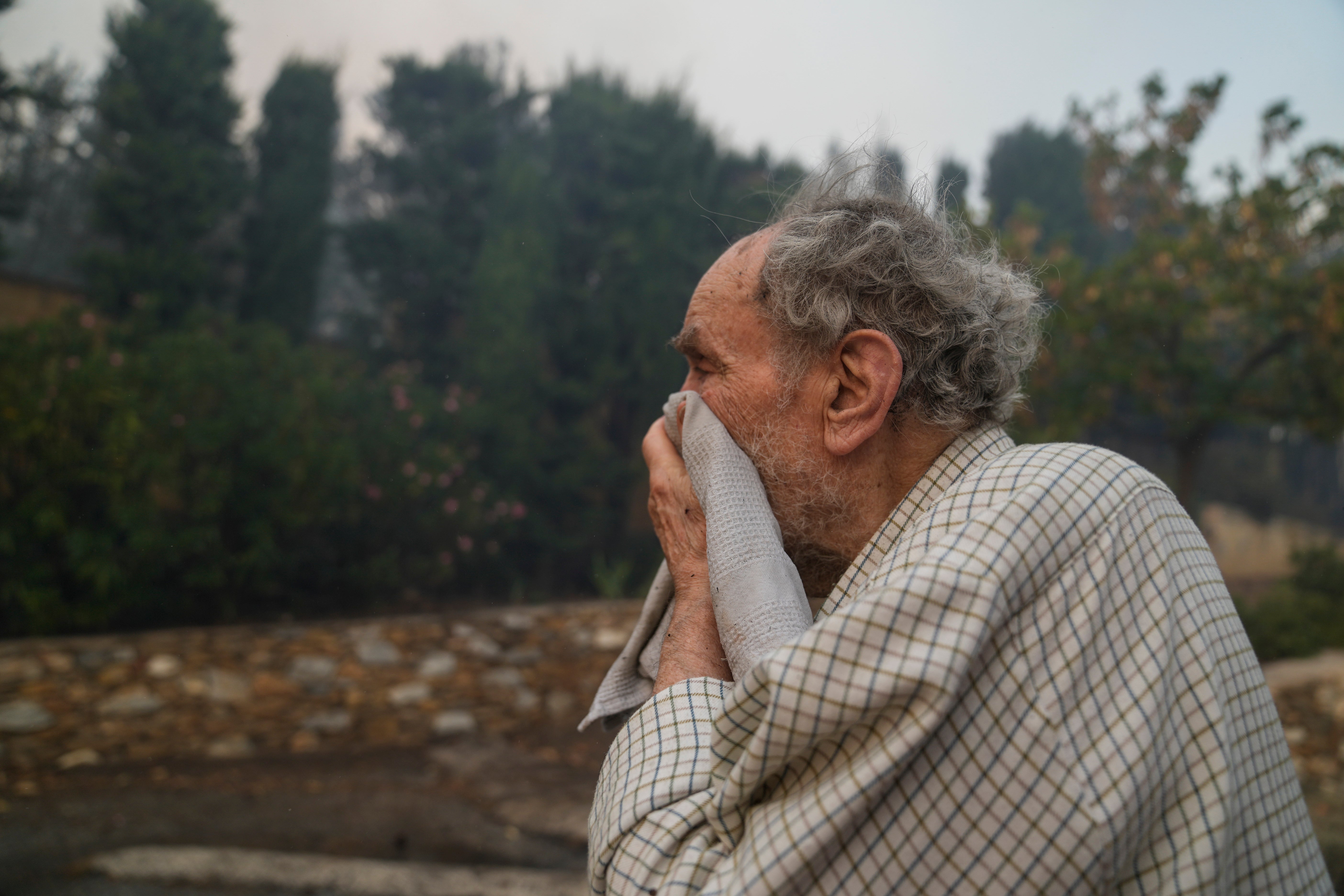 A man looks on as the fire comes near his house in Penteli