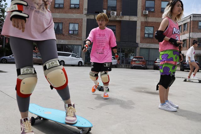 <p>Mina Zhao teaches a member of her women's club how to use a skateboard during a practise session in Beijing</p>