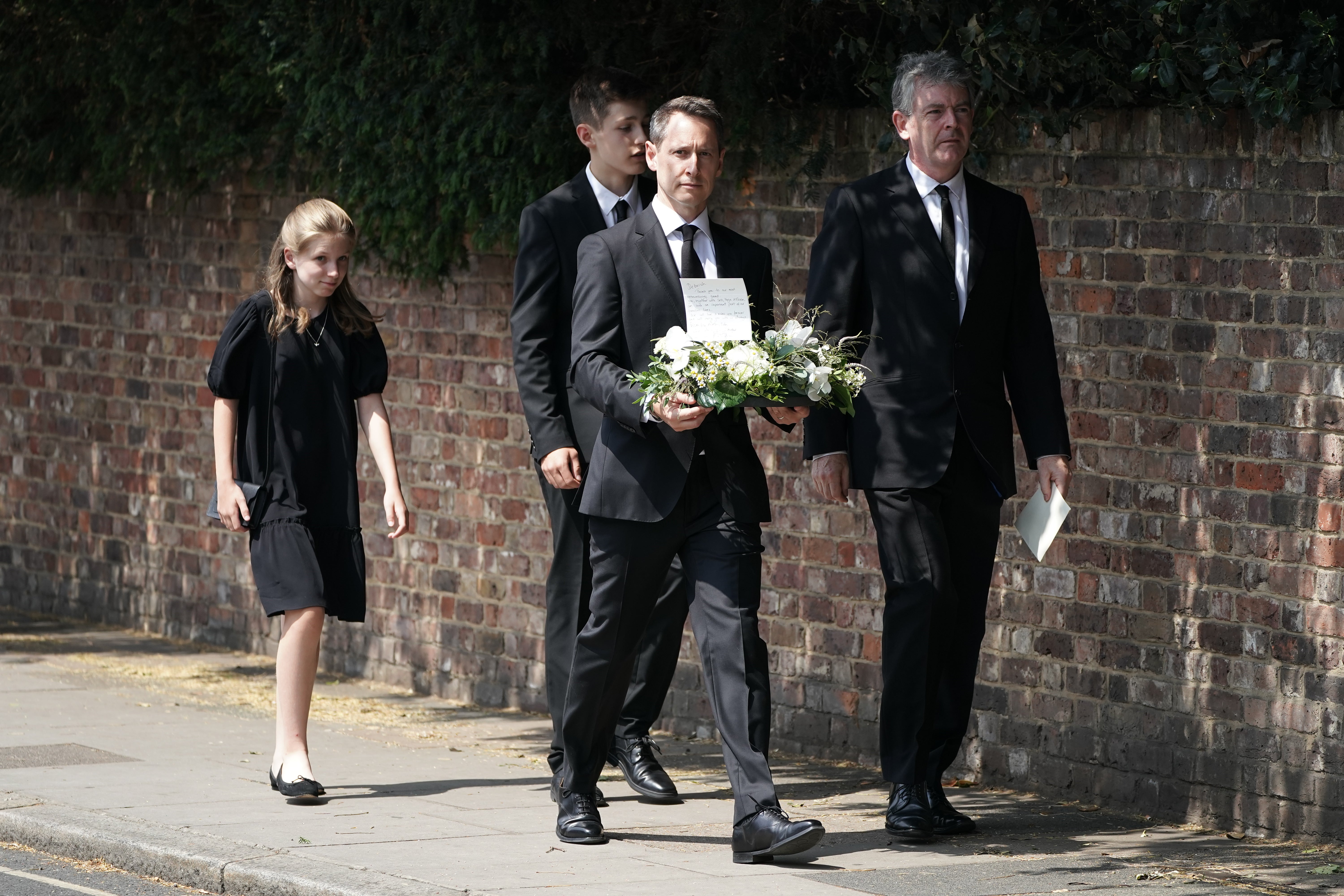 Mourners carrying flowers arrive at St Mary’s Church in Barnes, west London, for the funeral of Dame Deborah James (Aaron Chown/PA)