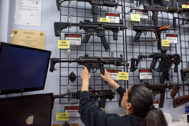 <p>Employee Gorety Mejia takes down a HK MP5 for a customer at Full Armor Firearms store in Houston, Texas on June 17, 2021. </p>