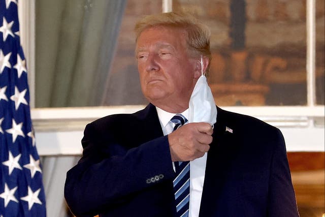 <p>U.S. President Donald Trump removes his mask upon return to the White House from Walter Reed National Military Medical Center on October 05, 2020 in Washington, DC</p>
