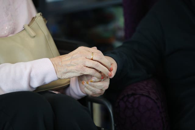 A care home resident and her daughter hold hands (Aaron Chown/PA)