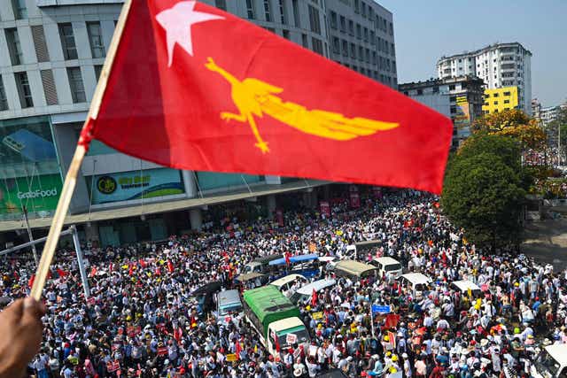 <p>A protester waves the National League for Democracy (NLD) flag while others take part in a demonstration against the military coup in Yangon.</p>