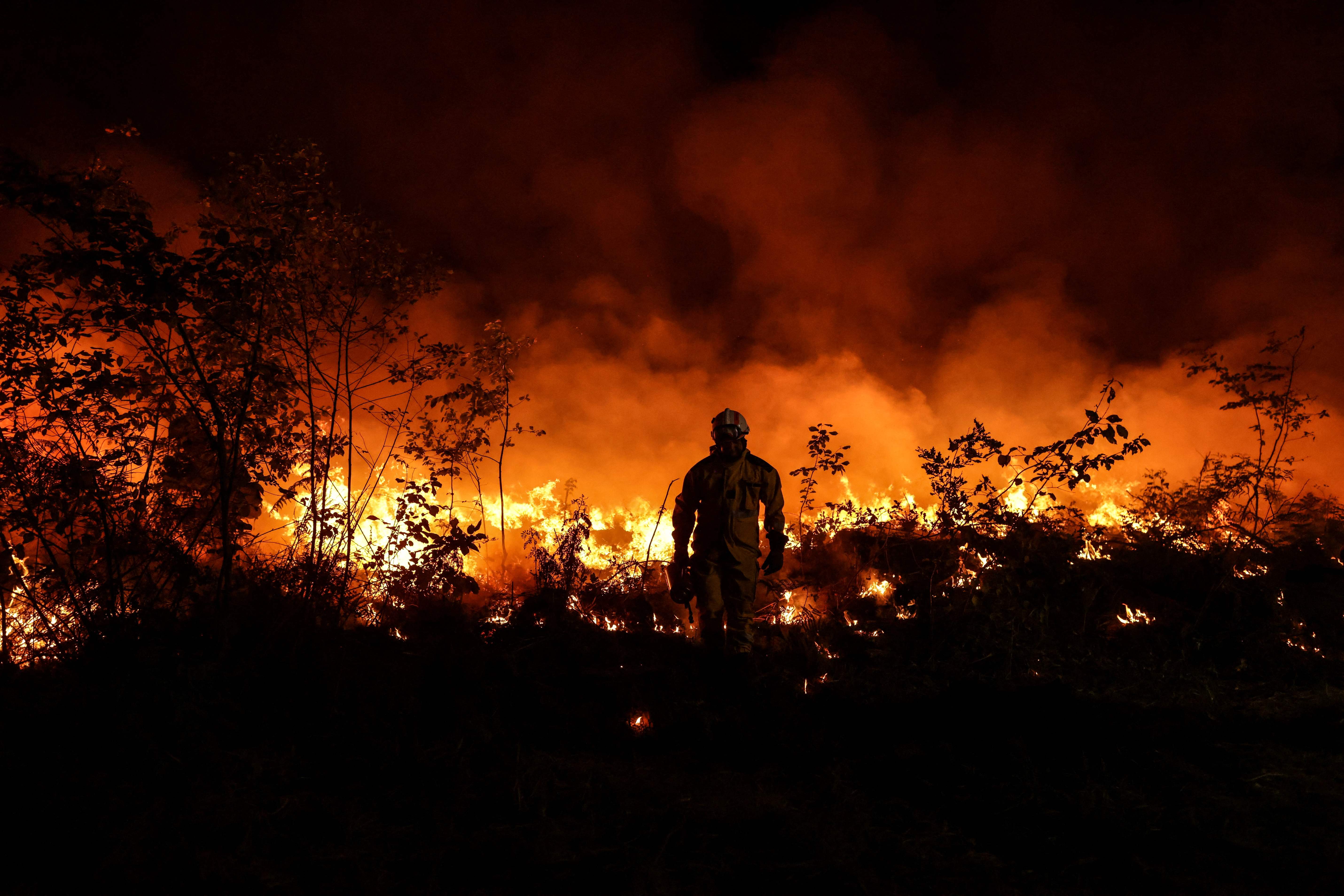 A tactical firefighter set fires to a plot of land as firefighters attempt to prevent the wildfire from spreading due to wind change in Gironde on 17 July.