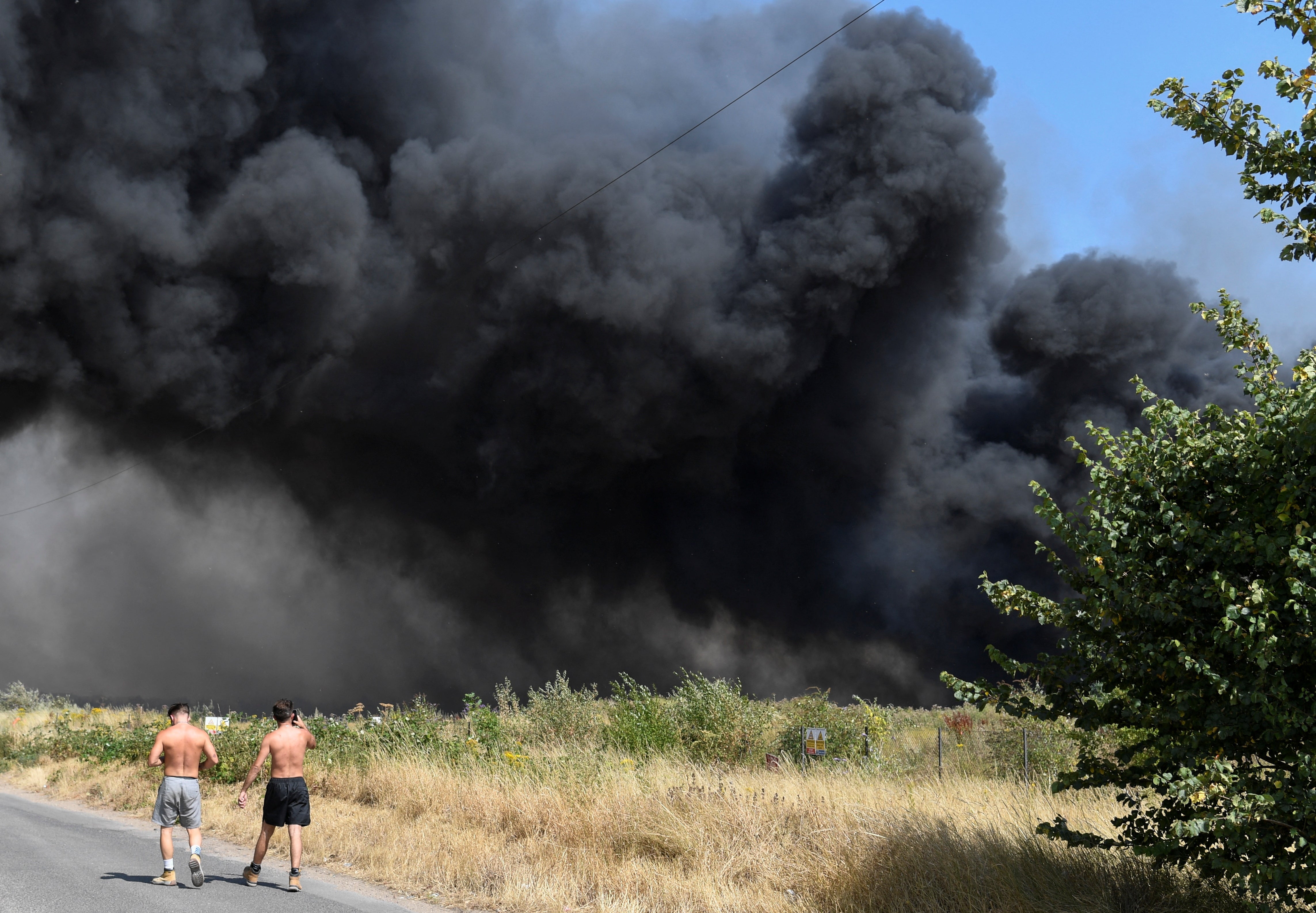 People watch a fire raging in east London during the heatwave