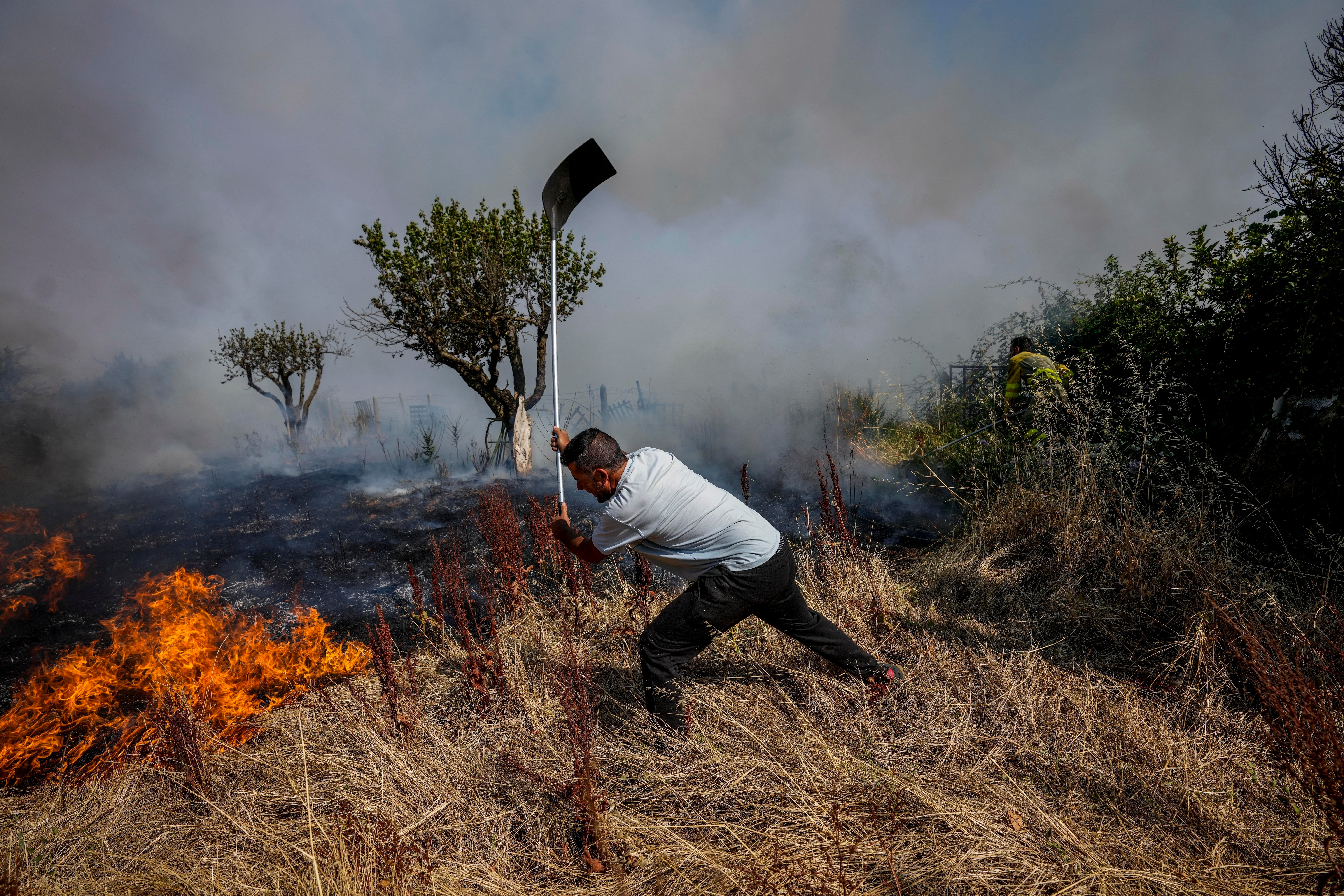 A local resident fights a forest fire with a shovel during a wildfire in Tabara, northwest Spain on Tuesday