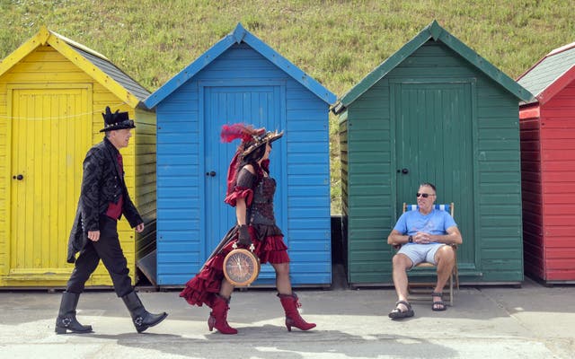 Karen and John Austin walk past a sunbather as they attend the Whitby Steampunk Weekend (Danny Lawson/PA)