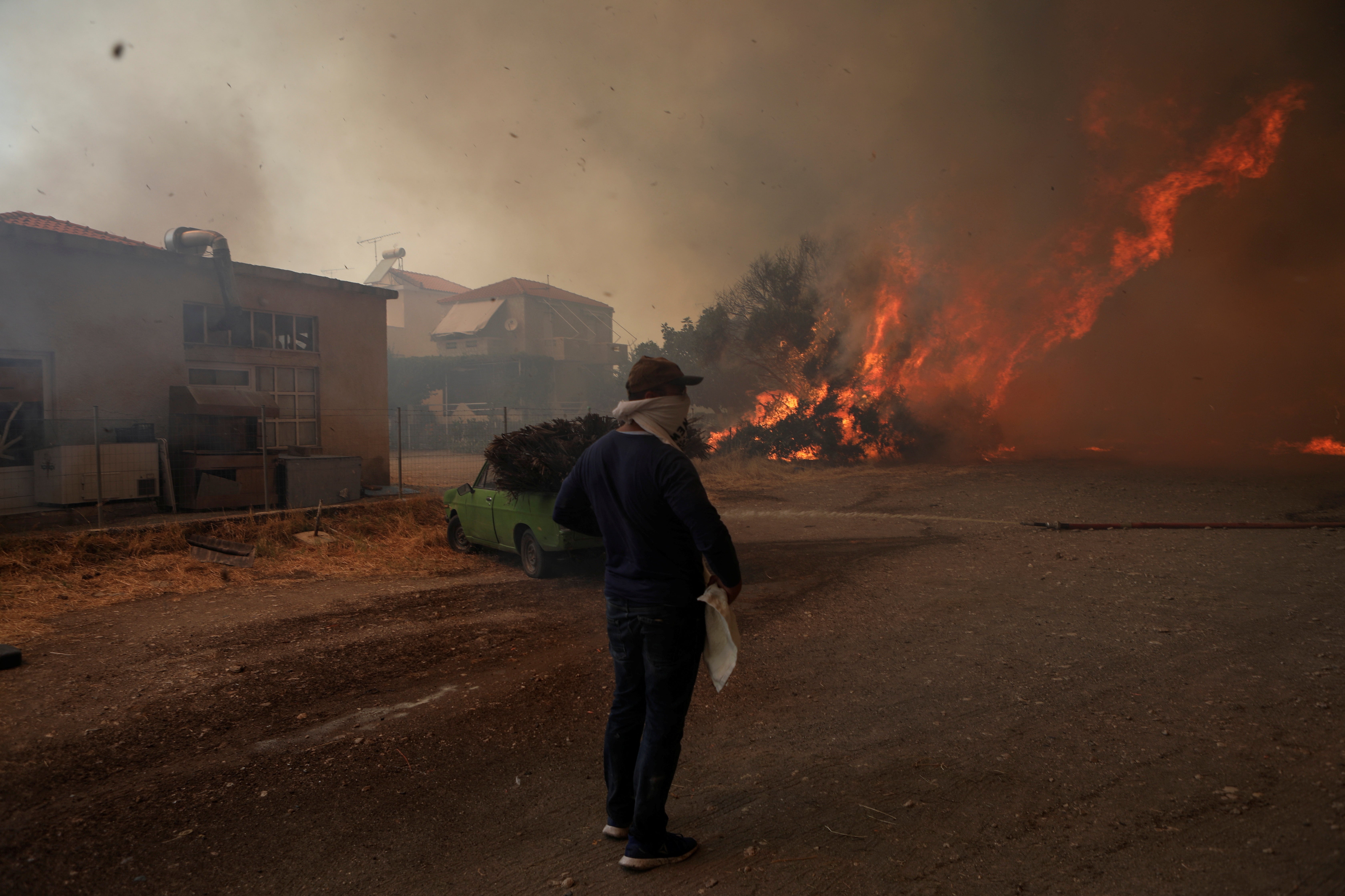 A local looks at wildfire burning in the village of Vatera, on the island of Lesbos
