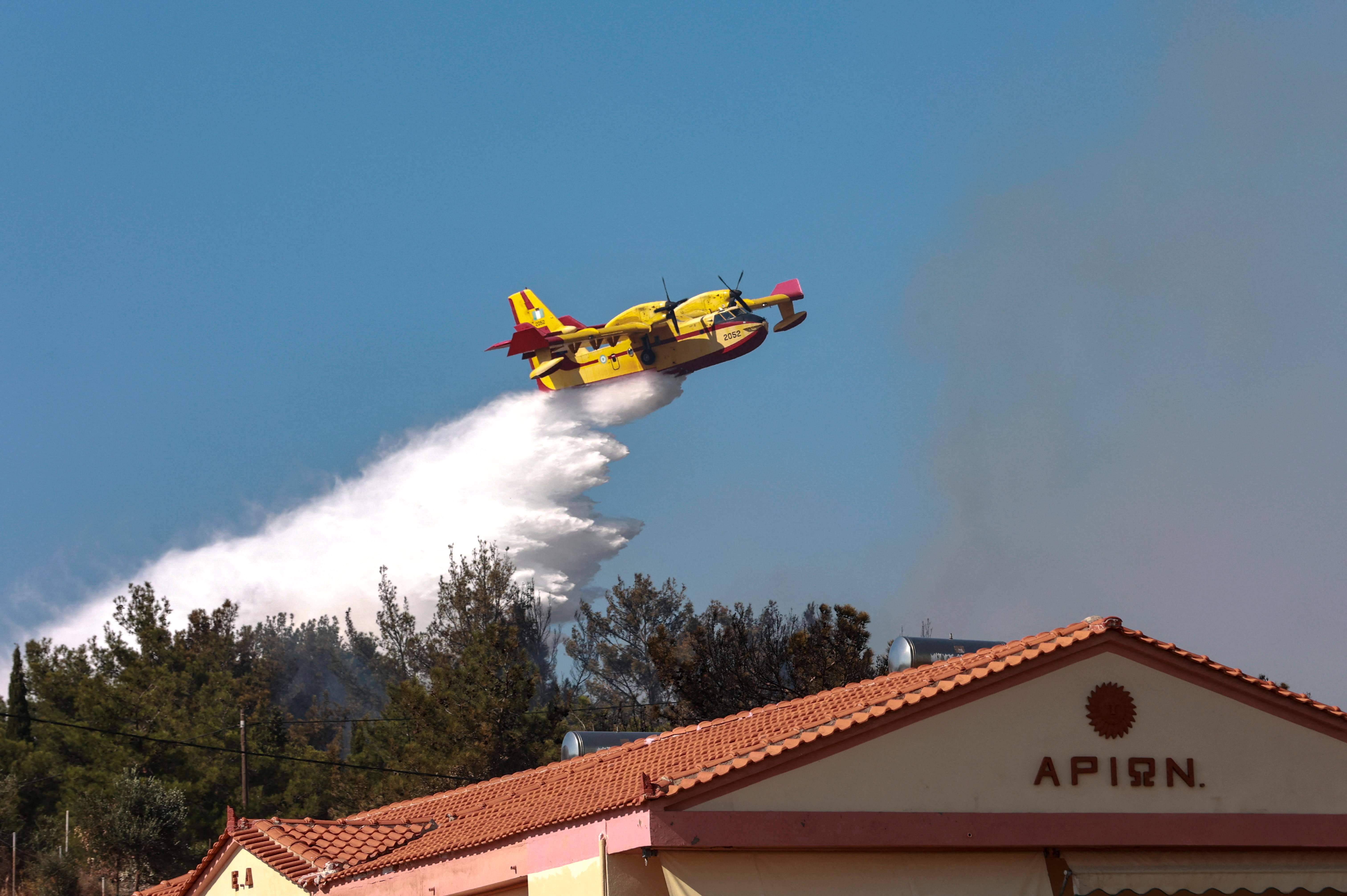 A canadair firefighting plane drops water at the wildfire approaching homes and hotels at Vatera coastal resort