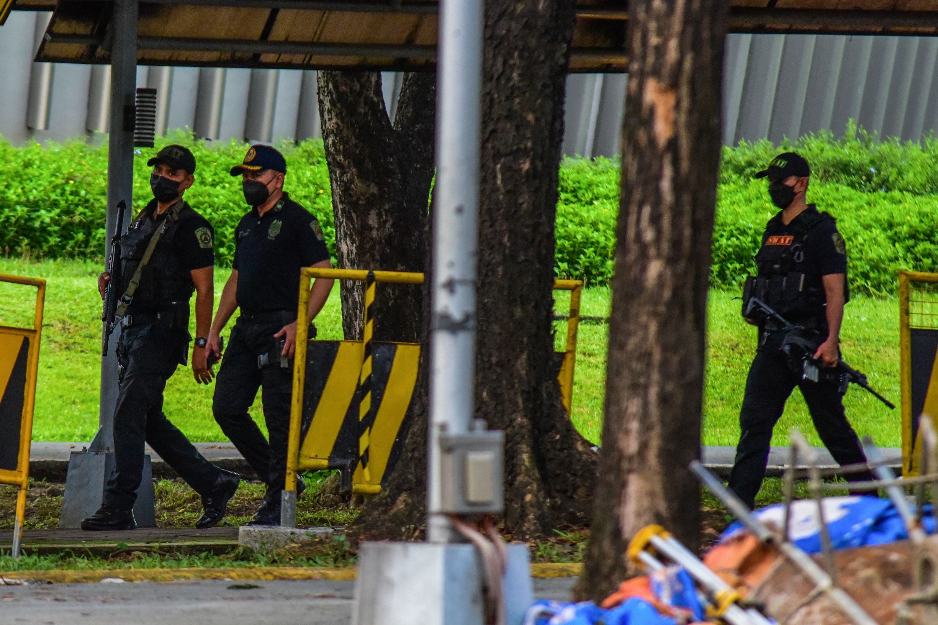 Police officers patrol the scene after three people were killed in a shooting at Ateneo de Manila University in Quezon City, suburban Manila, on 24 July