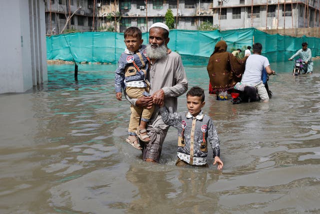 <p>Residents wade through a flooded street as the monsoon season hits Karachi</p>