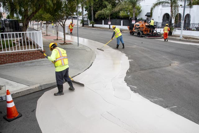Los trabajadores colocan una superficie más reflectante que puede ayudar a enfriar las carreteras en Los Ángeles