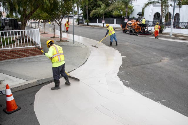 Los trabajadores colocan una superficie más reflectante que puede ayudar a enfriar las carreteras en Los Ángeles