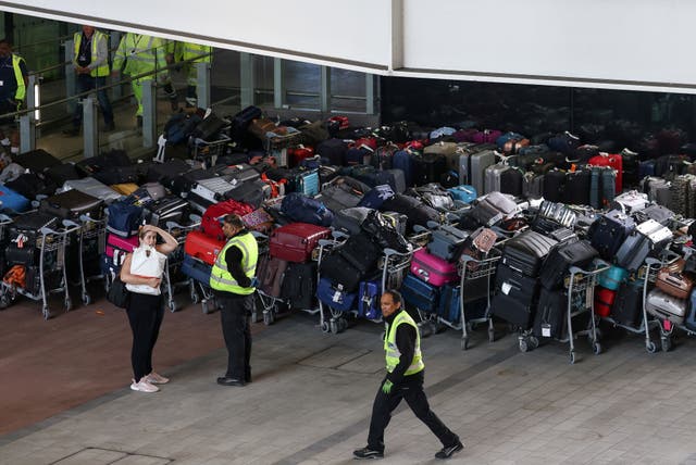 <p>Airport workers stand next to lines of passenger luggage </p>