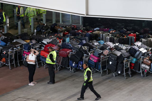 <p>Airport workers stand next to lines of passenger luggage </p>