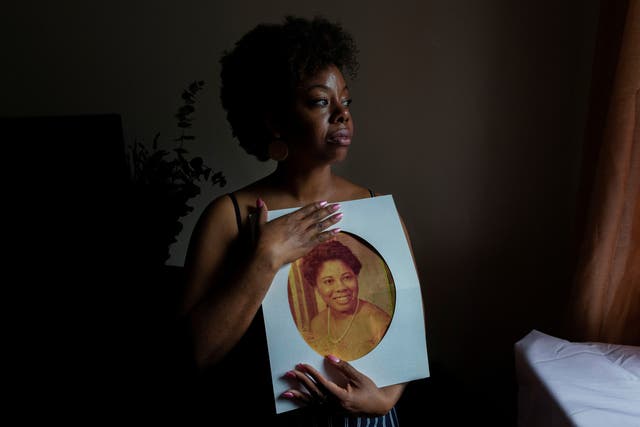 <p>Nicole Sharpe holds a photograph of her mother, Heather Hurley, who was killed by her father when Sharpe was a teenager</p>