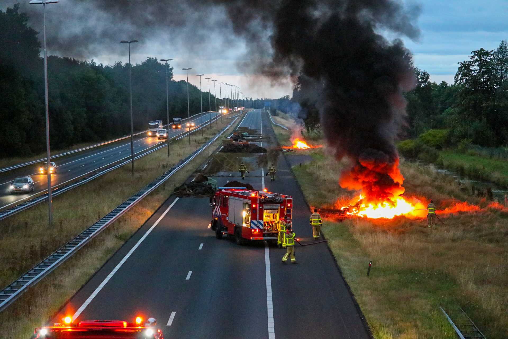 Firefighters at the scene as farmers set fire to manure and hay bales during a protest along the A50 in Apeldoorn