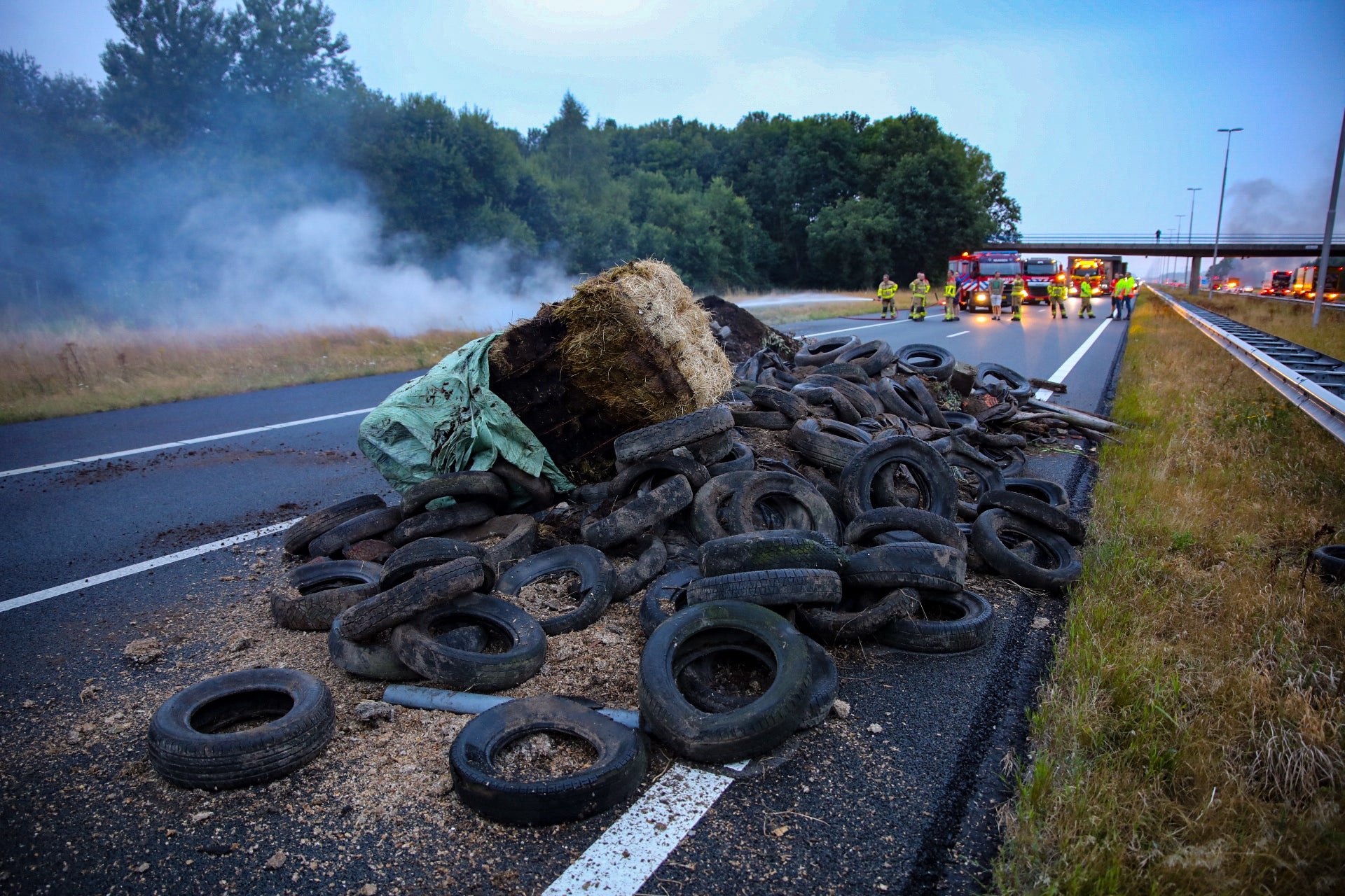 A pile of manure, tires and hay bales on fire