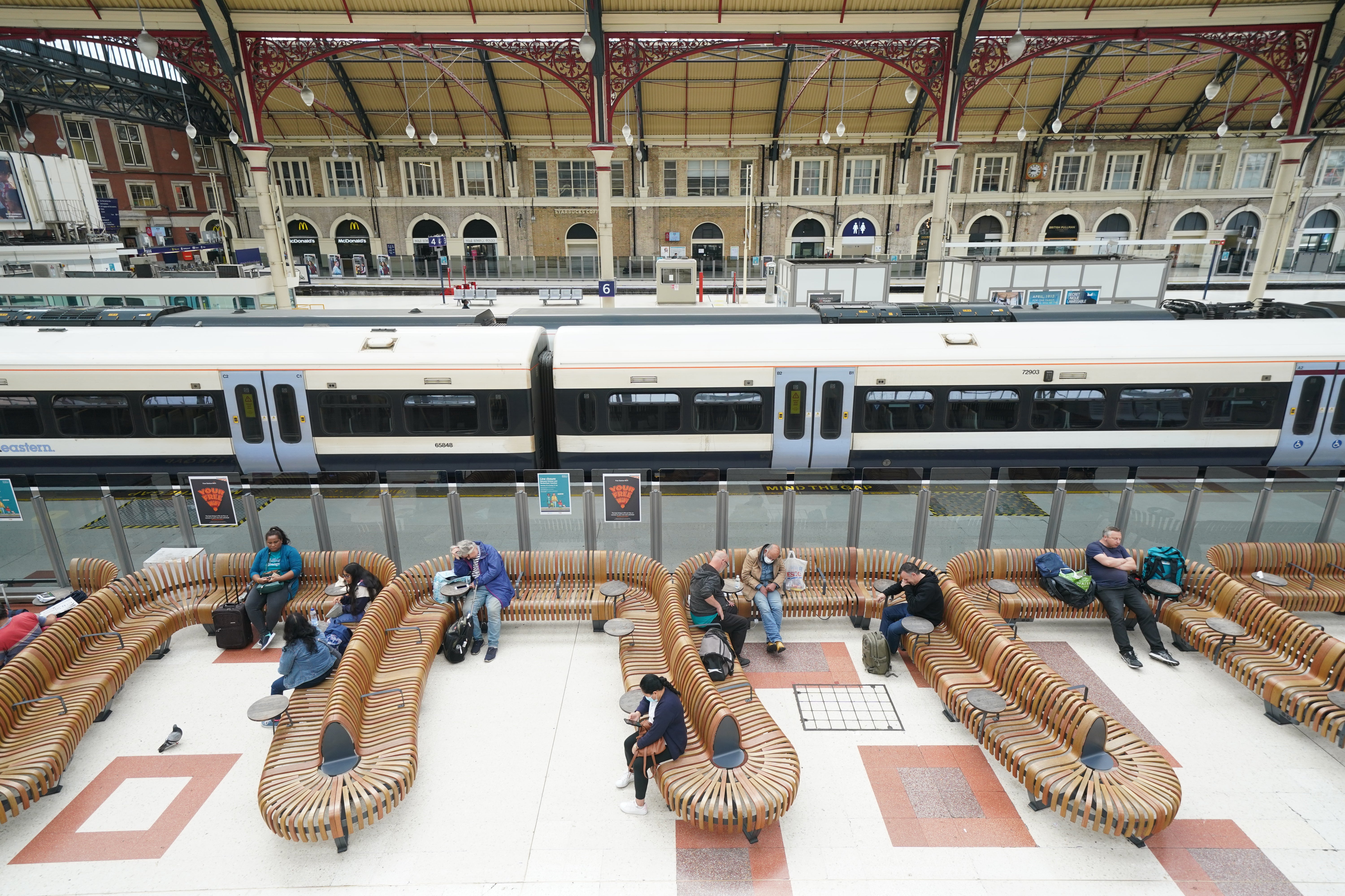 Passengers sit in a waiting area during rush hour at Victoria station in London (Kirsty O’Connor/PA)